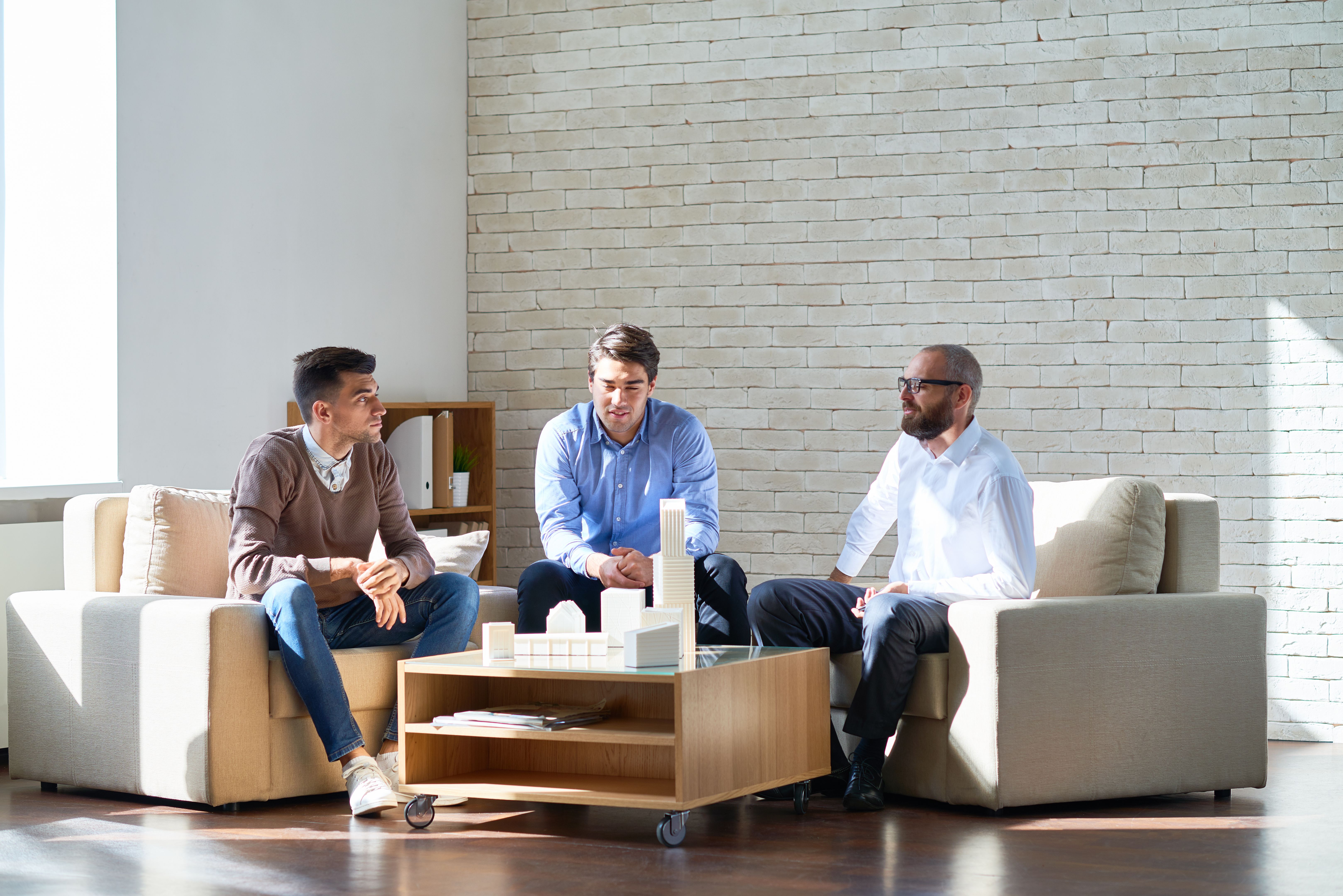 Contemporary workers with building miniature in office Contemporary workers with building miniature in office