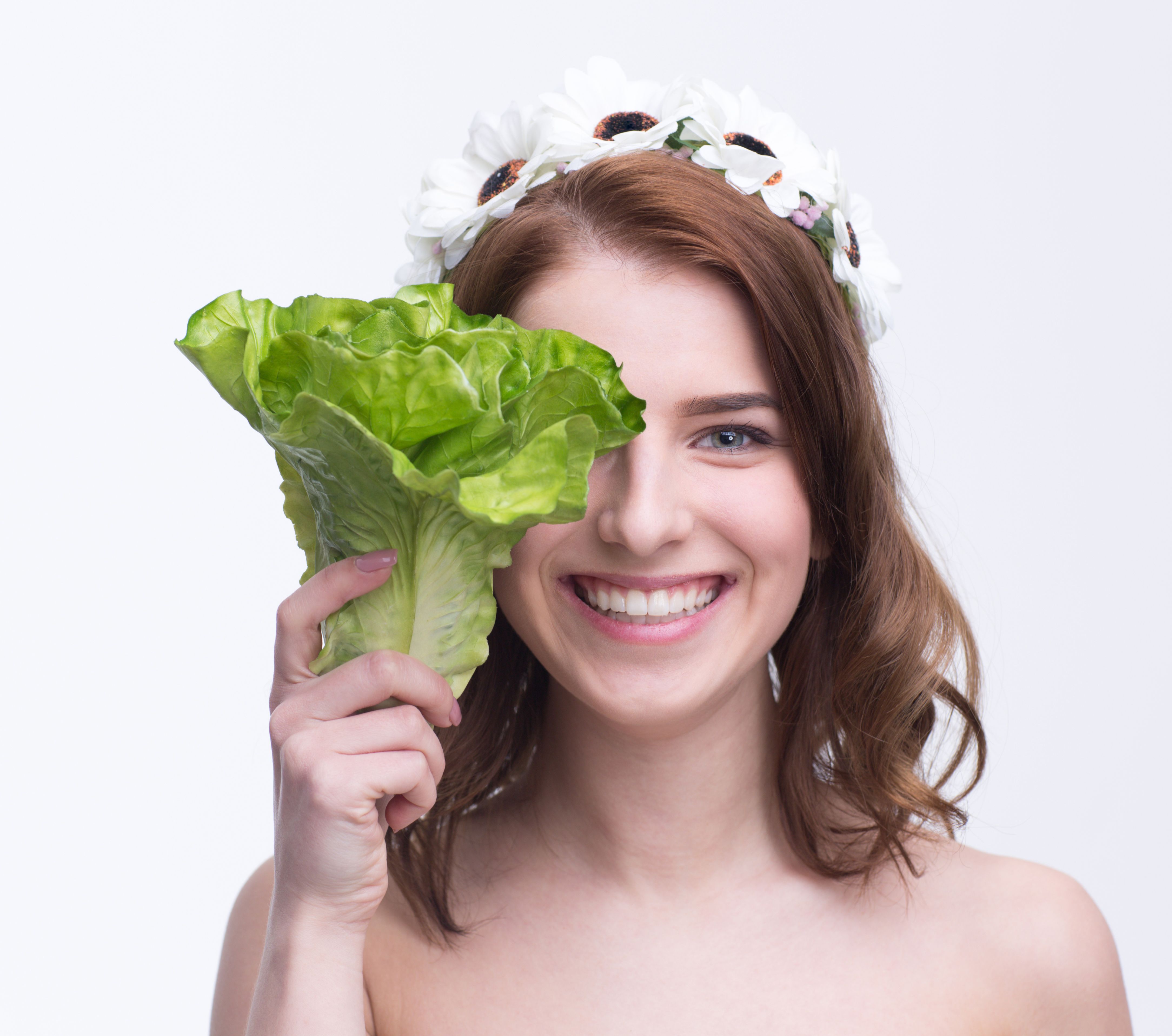 woman covering her eye with salad