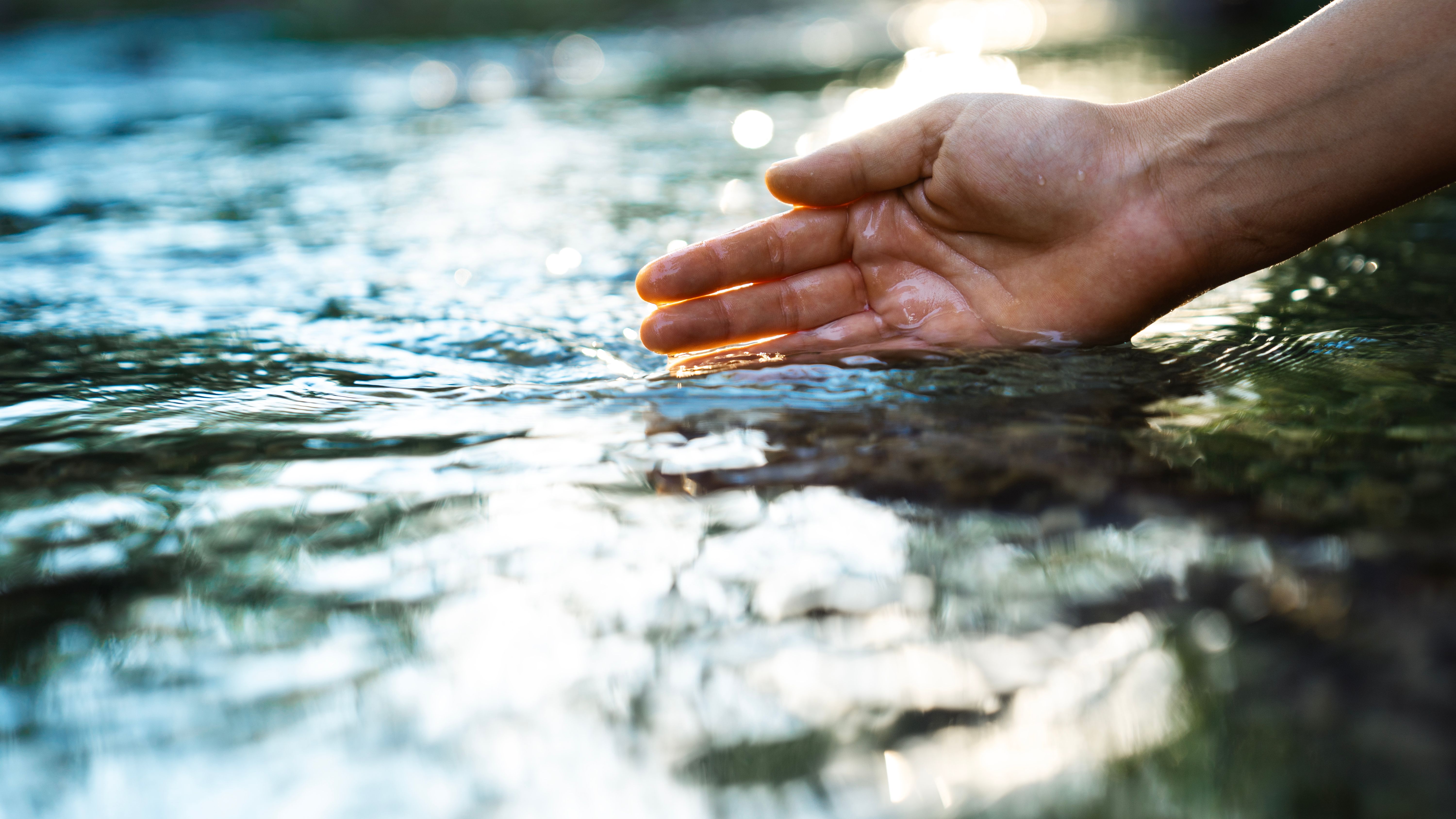 A female hand touching the river water A female hand touching the river water
