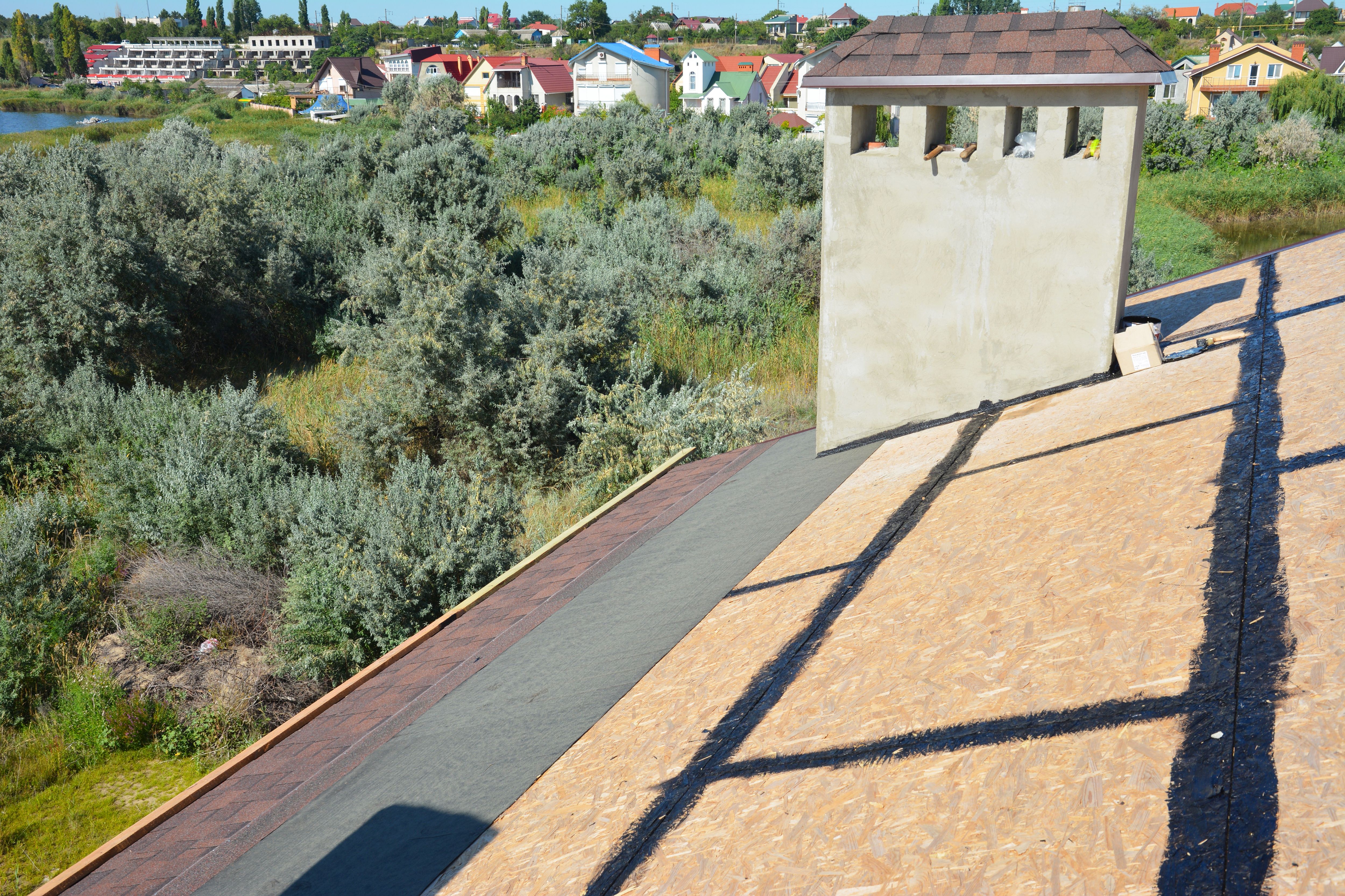 Asphalt shingles roofing construction, repair, installation, replace, renovation. Laying asphalt shingles with vapor barrier and chimney waterproofing on the house roof. Roofing Construction Details.