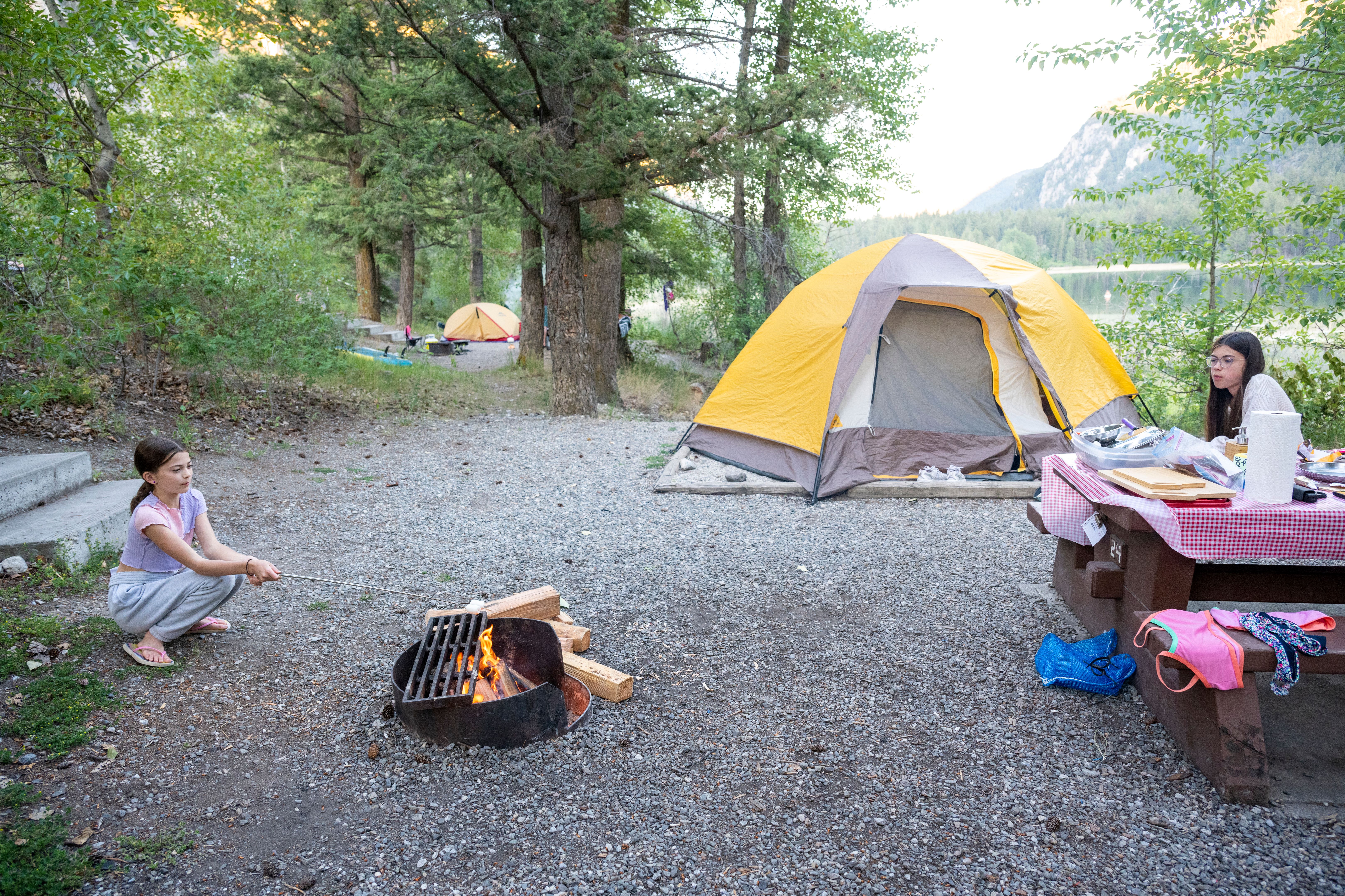 Young girls enjoy meal at picnic table in campsite