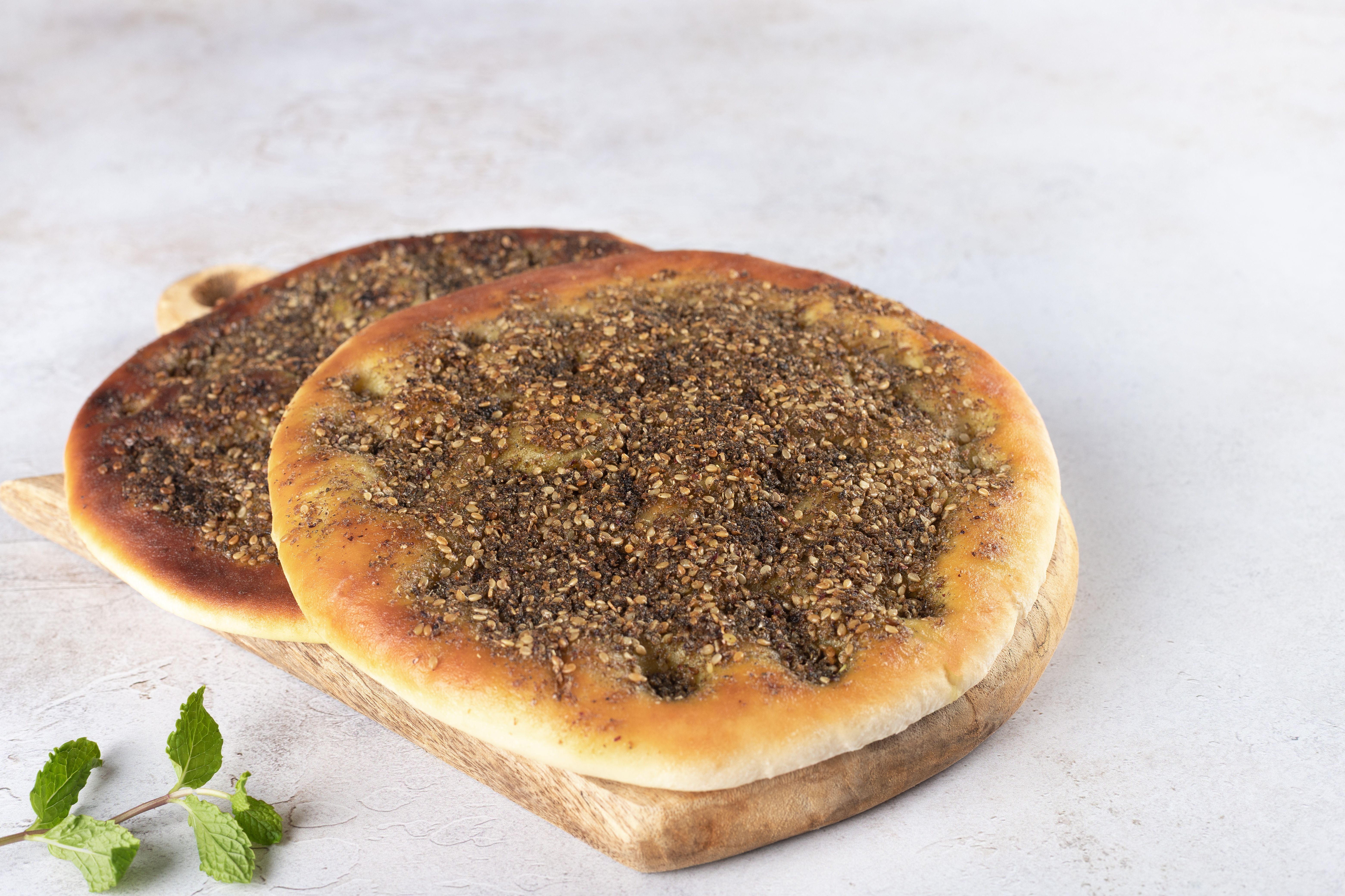 Flat bread Zaatar Manakish on wooden board background. Arabic food.