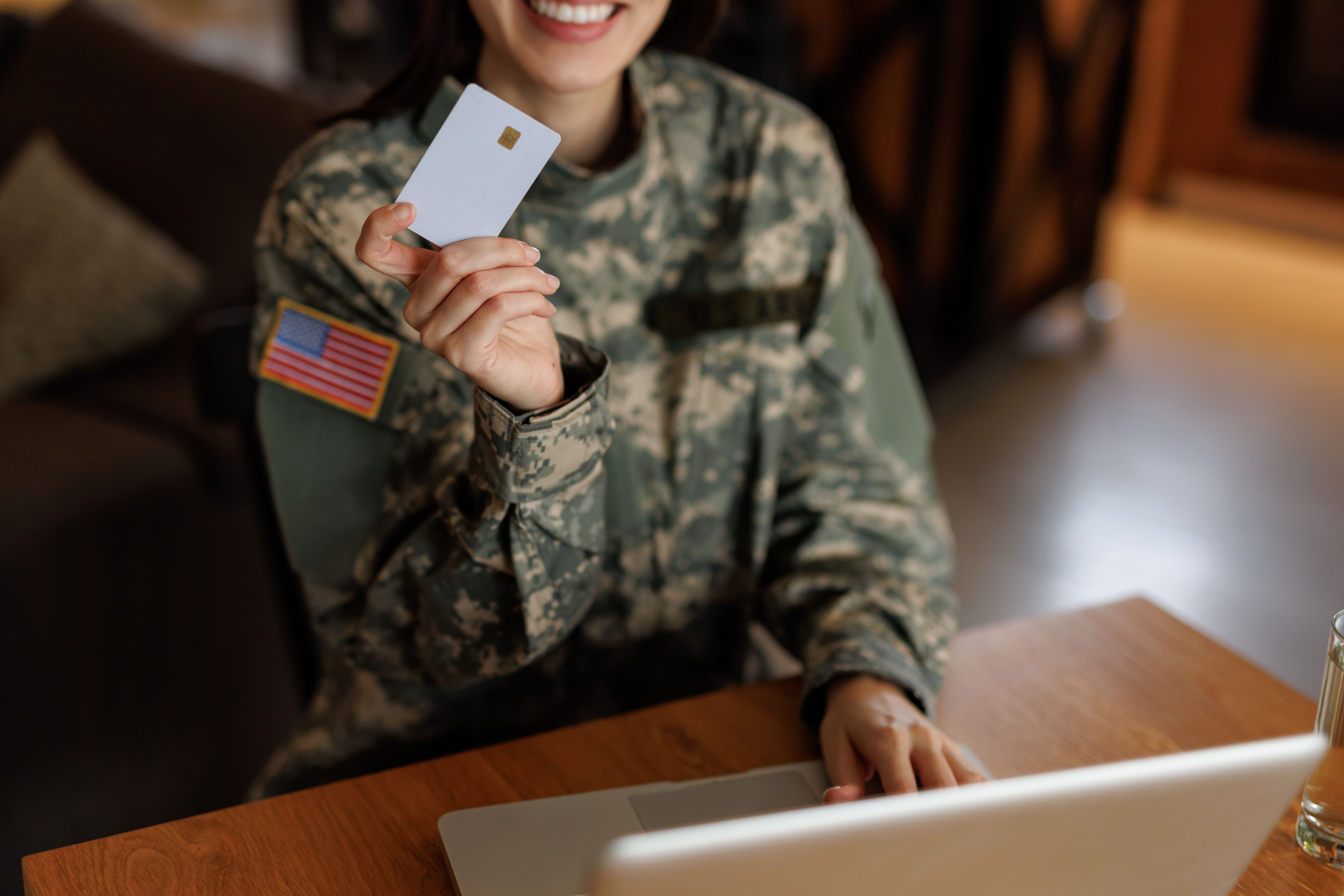 Smiling United States Army soldier shopping online using laptop and credit card Smiling United States Army soldier shopping online using laptop and credit card