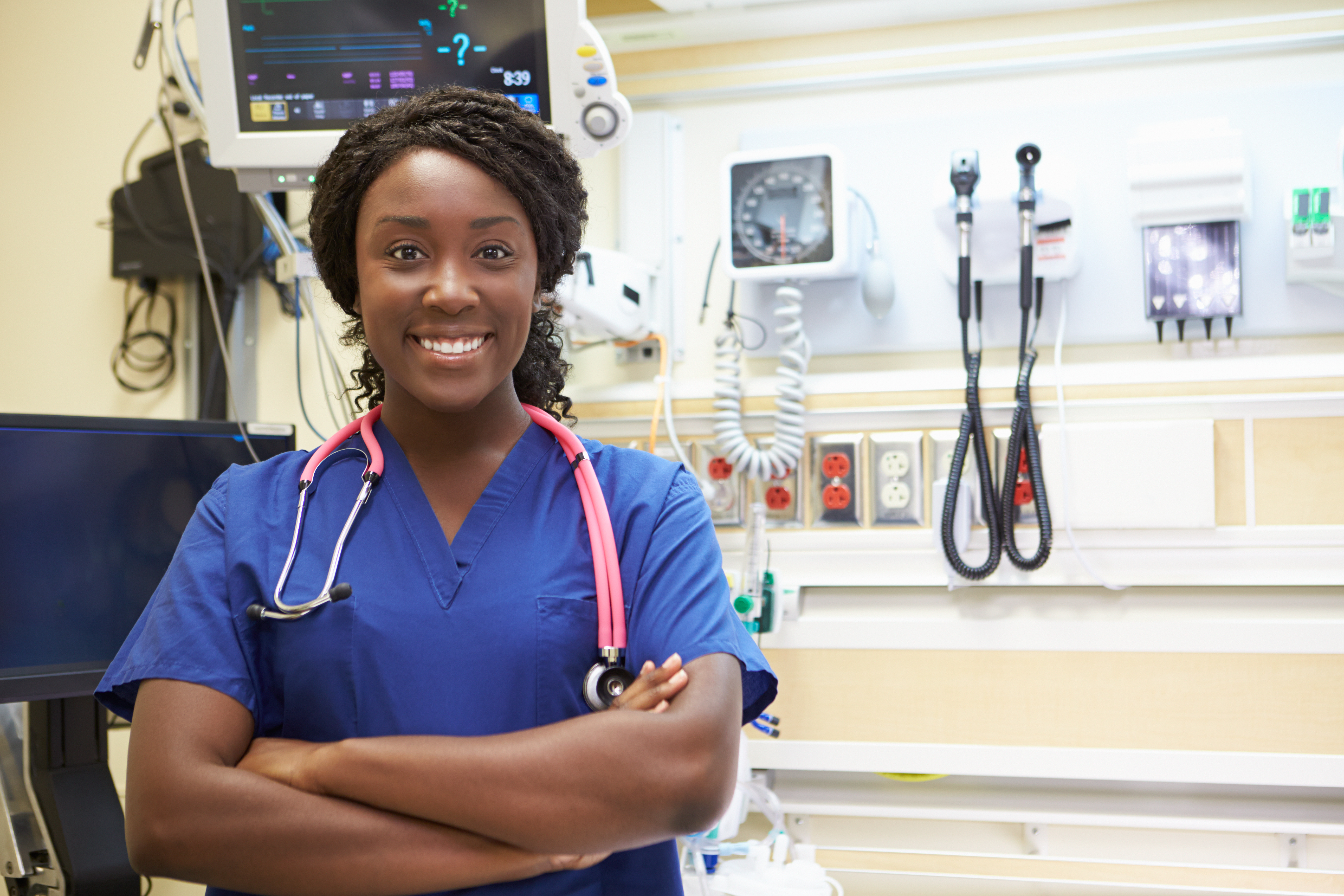 Smiling female nurse with arms folded at a medical facility Smiling female nurse with arms folded at a medical facility