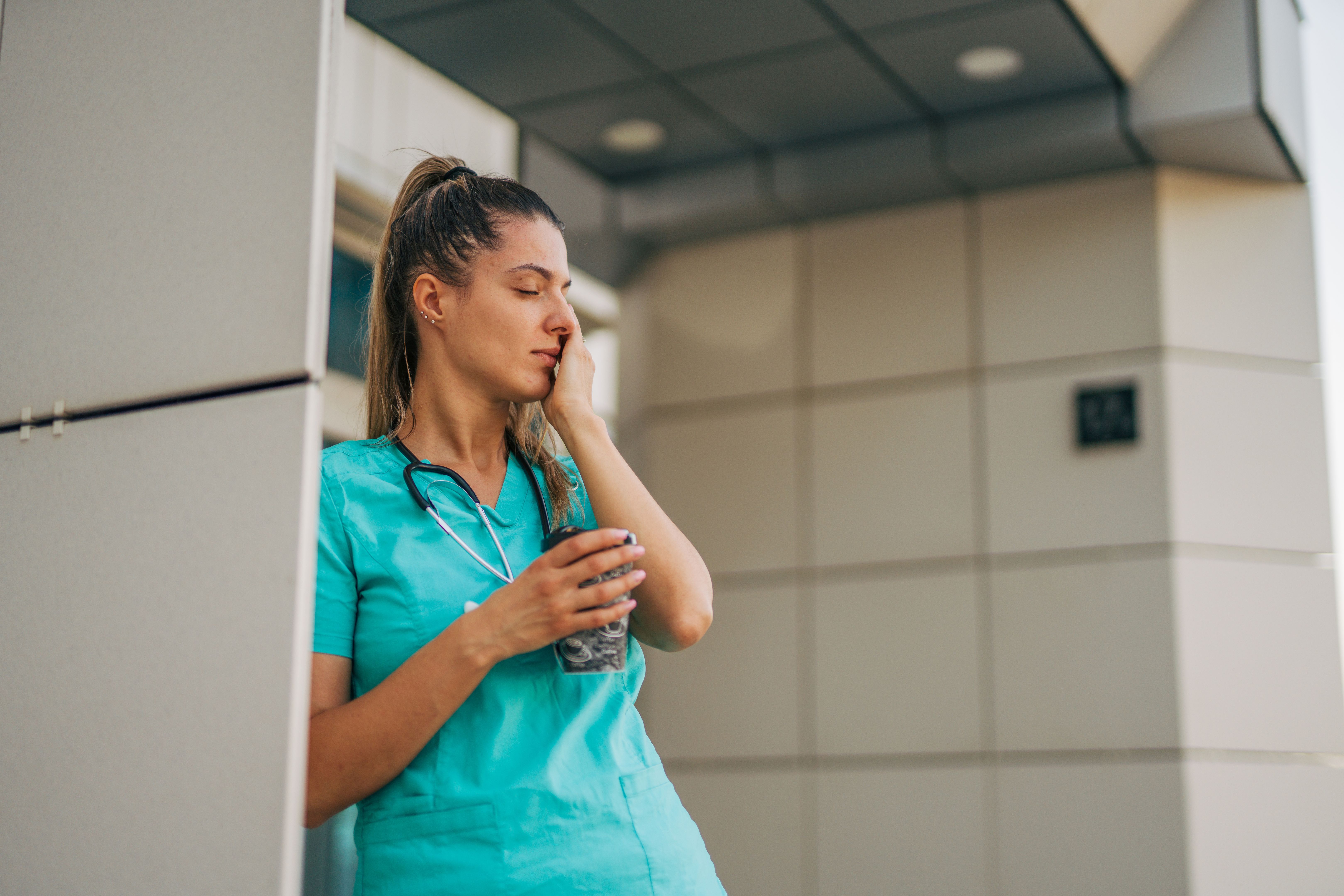 Shot of a female nurse looking stressed while standing out of hospital Shot of a female nurse looking stressed while standing out of hospital