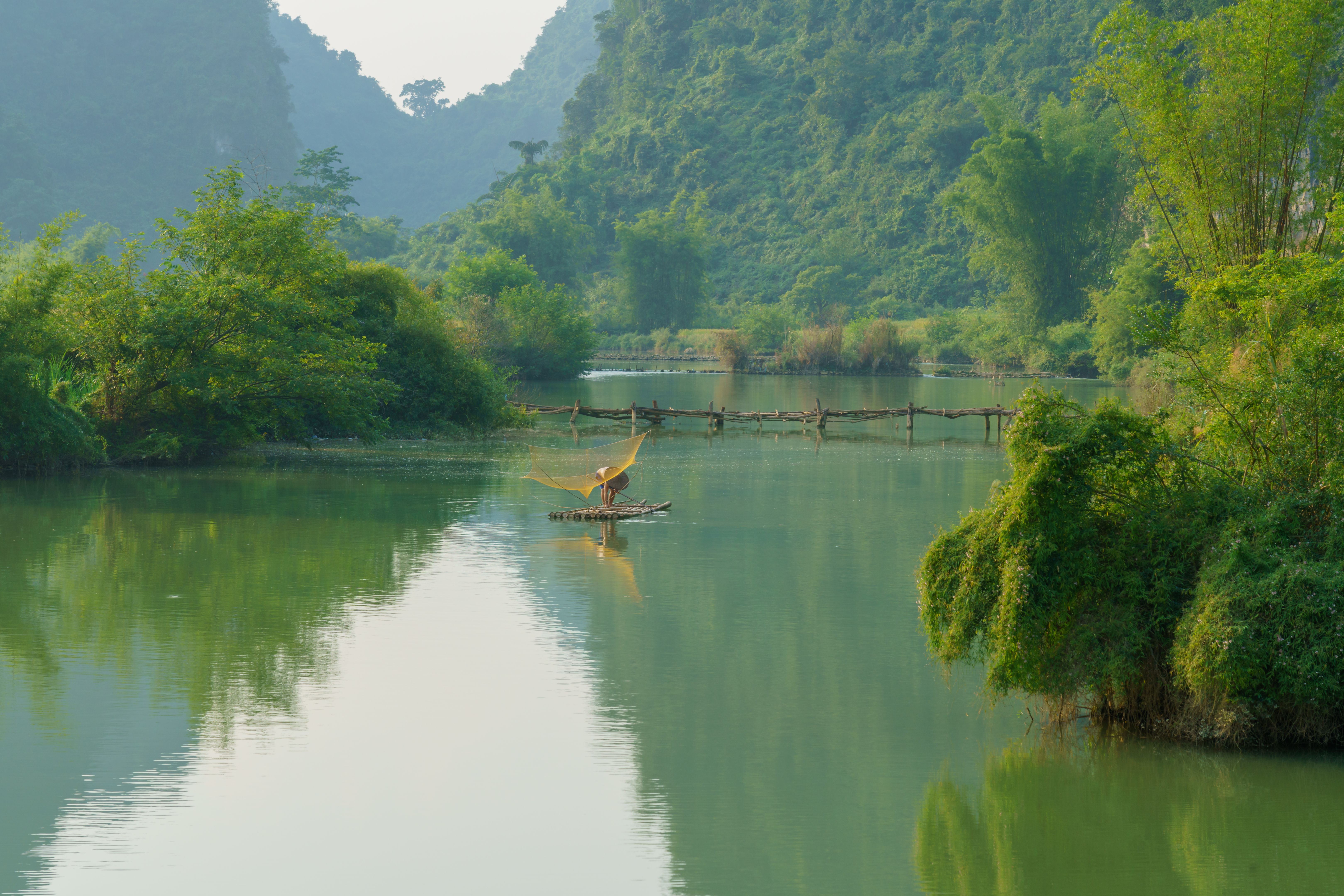 Landscape river scene with stream and a man fishing with net in Trung Khanh, Cao Bang province, Vietnam Landscape river scene with stream and a man fishing with net in Trung Khanh, Cao Bang province, Vietnam
