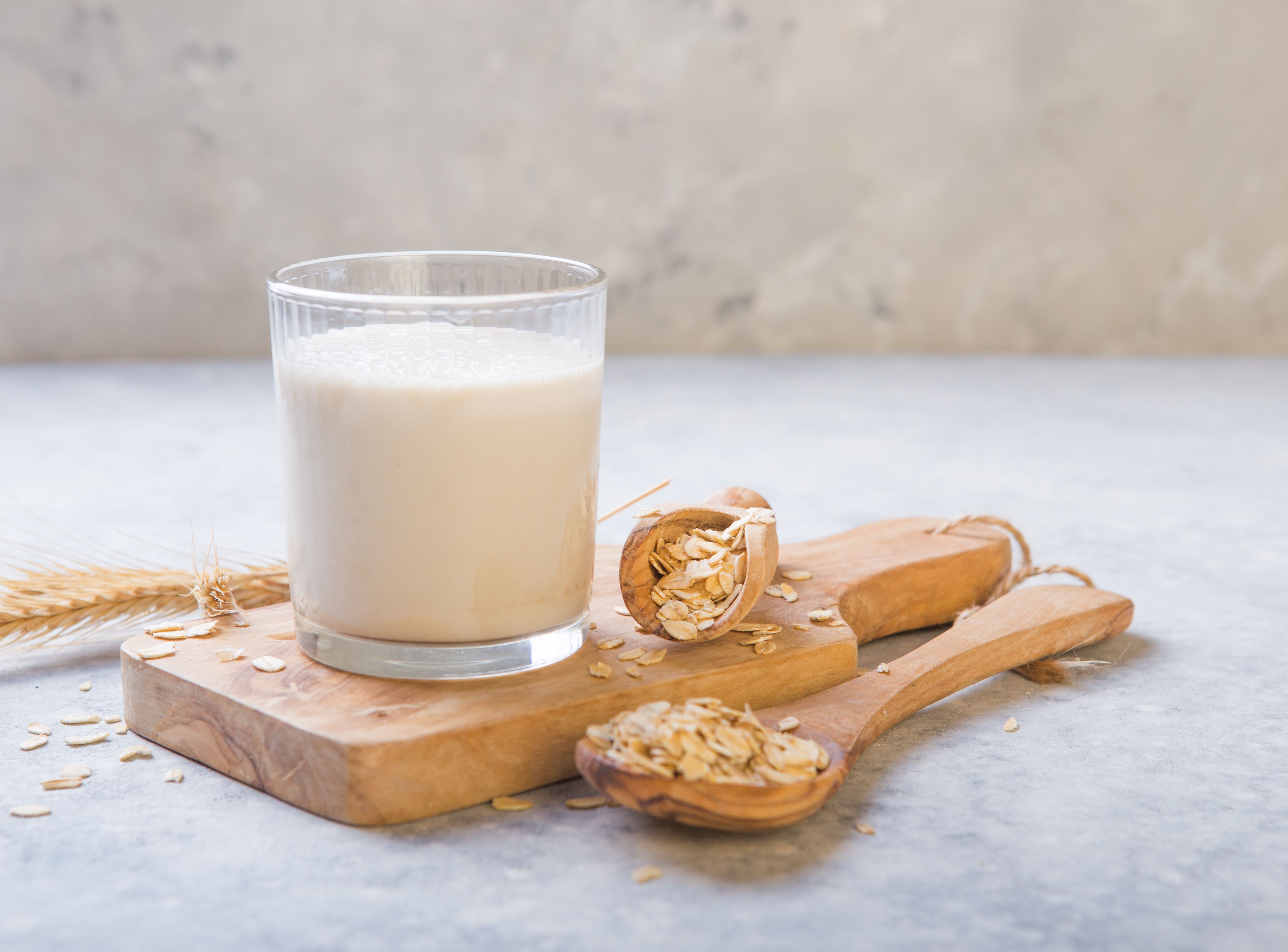 The concept of a vegetarian diet. Oat milk in the glass with jug of milk and oat.  Light background