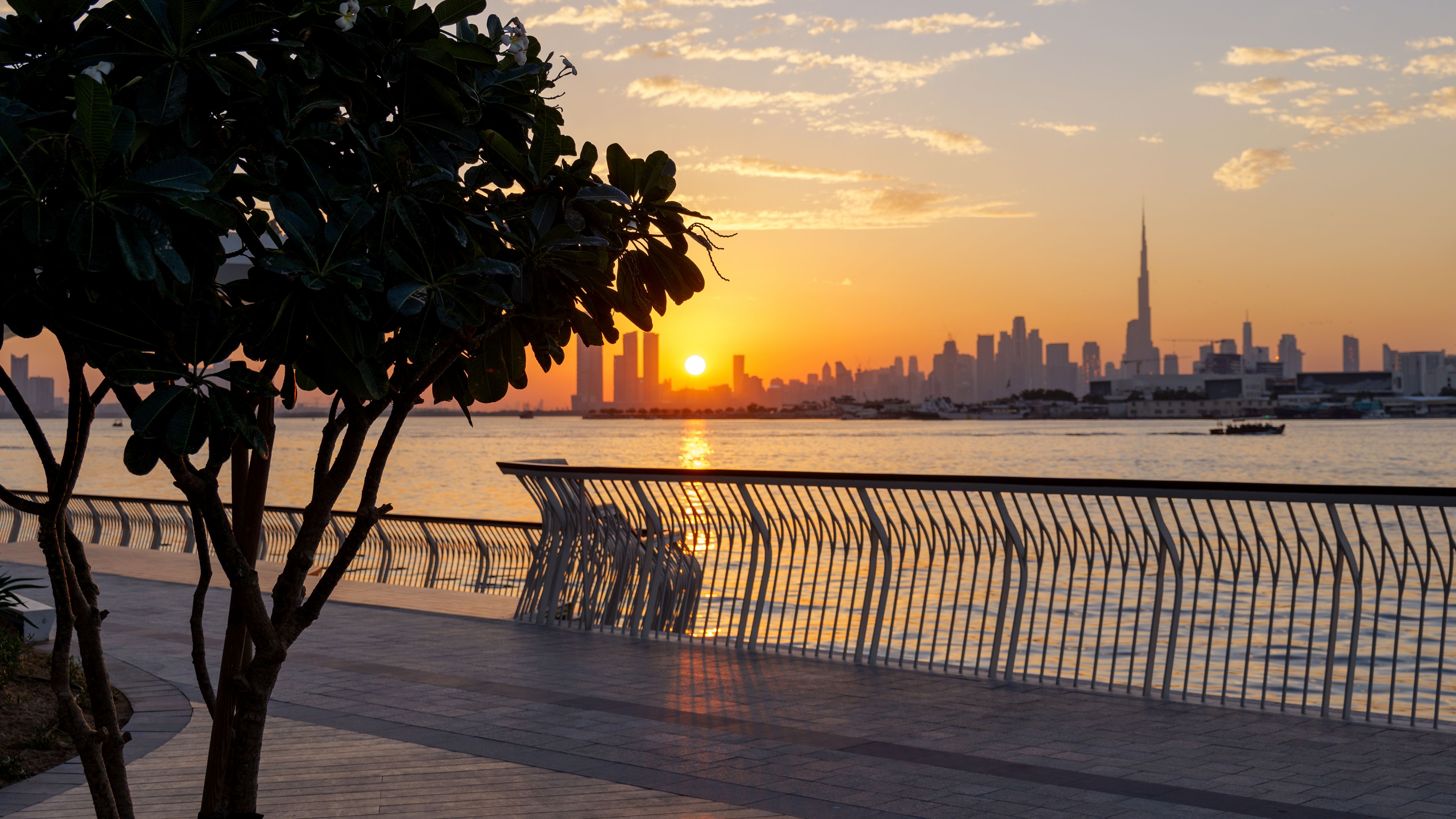 Panoramic sunset view of Dubai Downtown skyline and Dubai Creek canal from Dubai Creek Harbour promenade