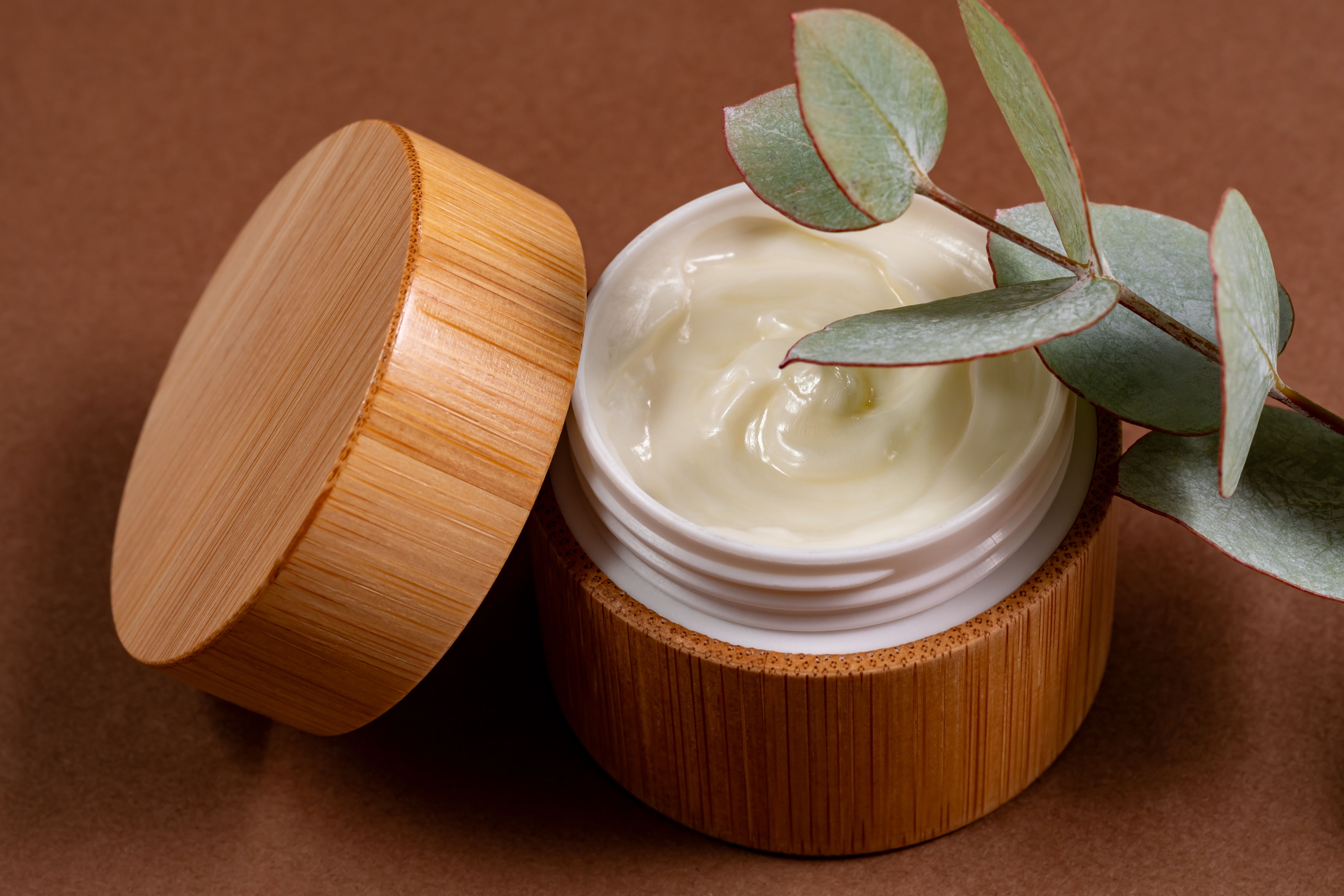 Face or body cream in bamboo jar with natural eucalyptus extracts and oils. Skin care cosmetics. Herbal treatment.