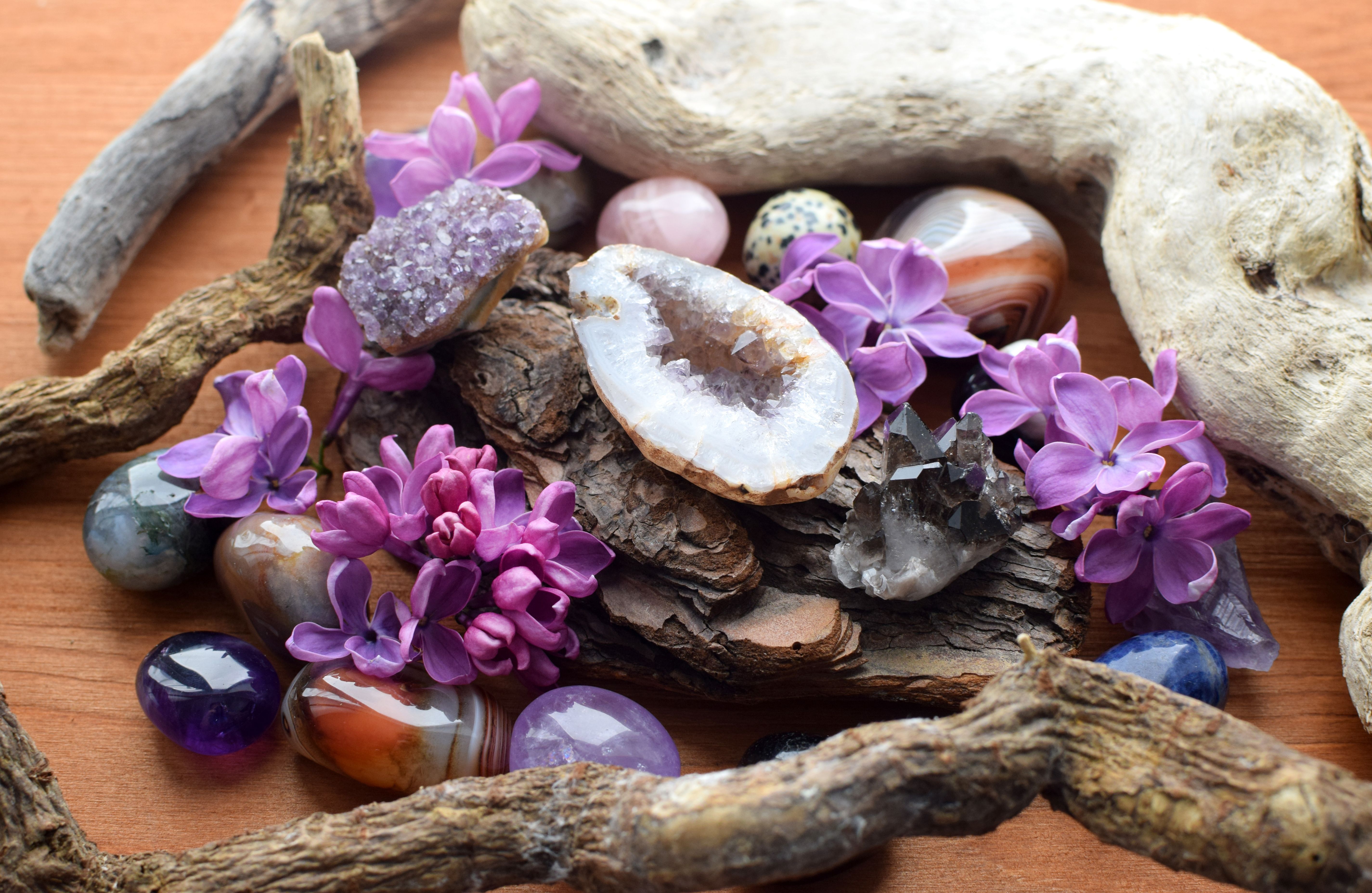 Beautiful geode of purple amethyst crystals on wooden background with lilac flowers