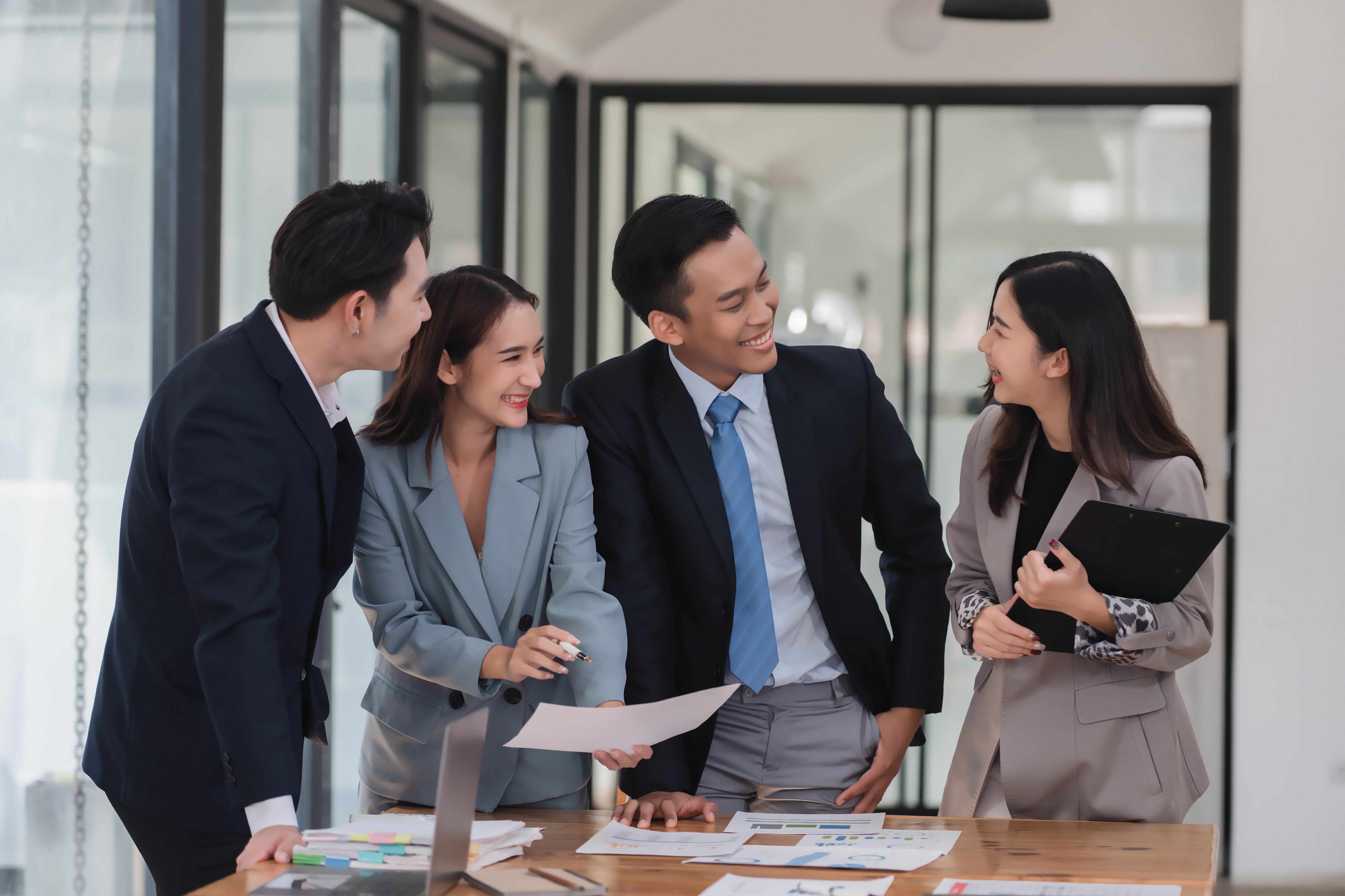 Young motivated Asian business team discussing oh business strategy in the modern meeting room.