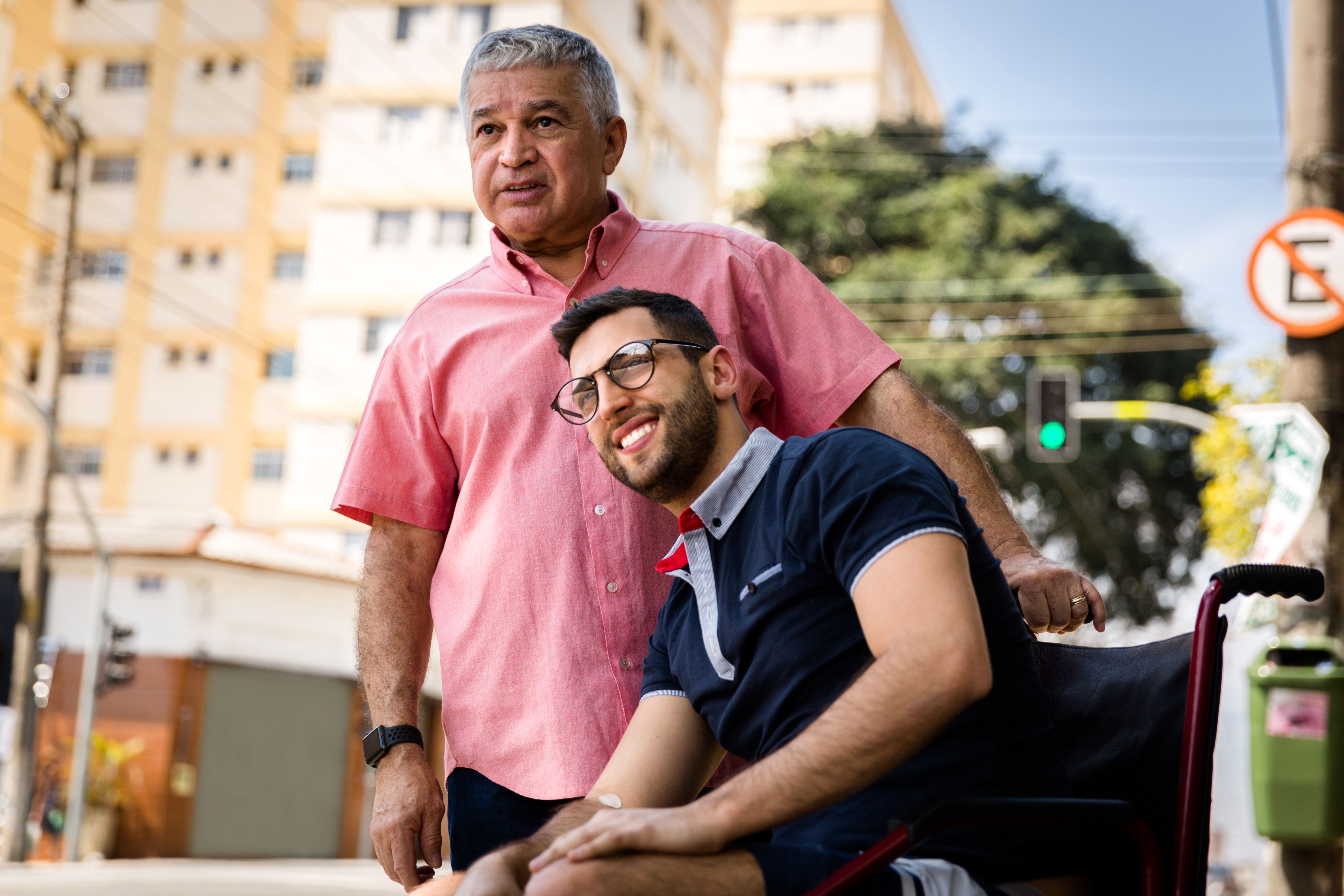 Dad and his son sitting in his wheelchair waiting for the bus