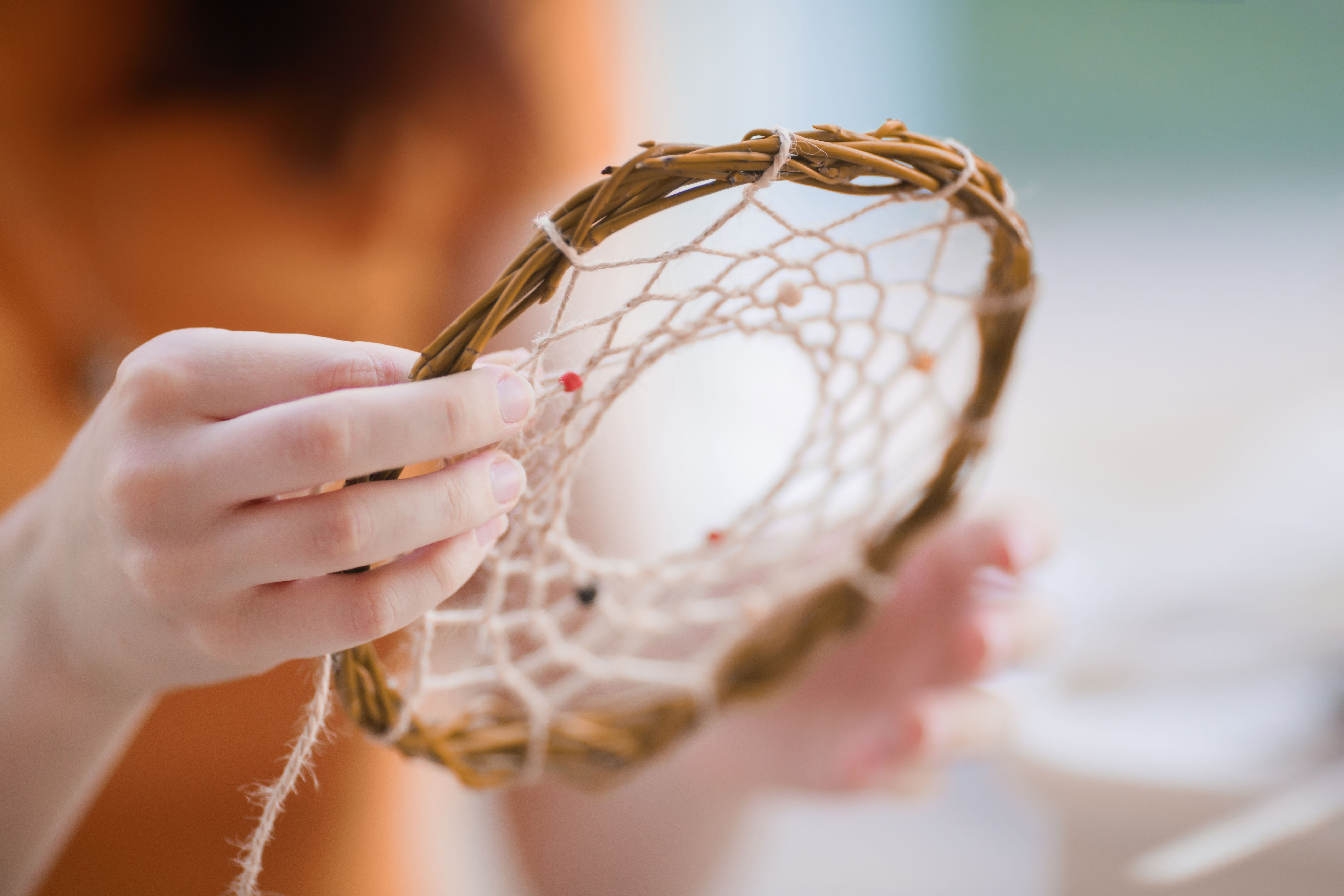 Dream catcher creation in art studio. Young woman making decoration accessory for bedroom, closeup photo. Workshop, hobby, handicraft, creativity concept