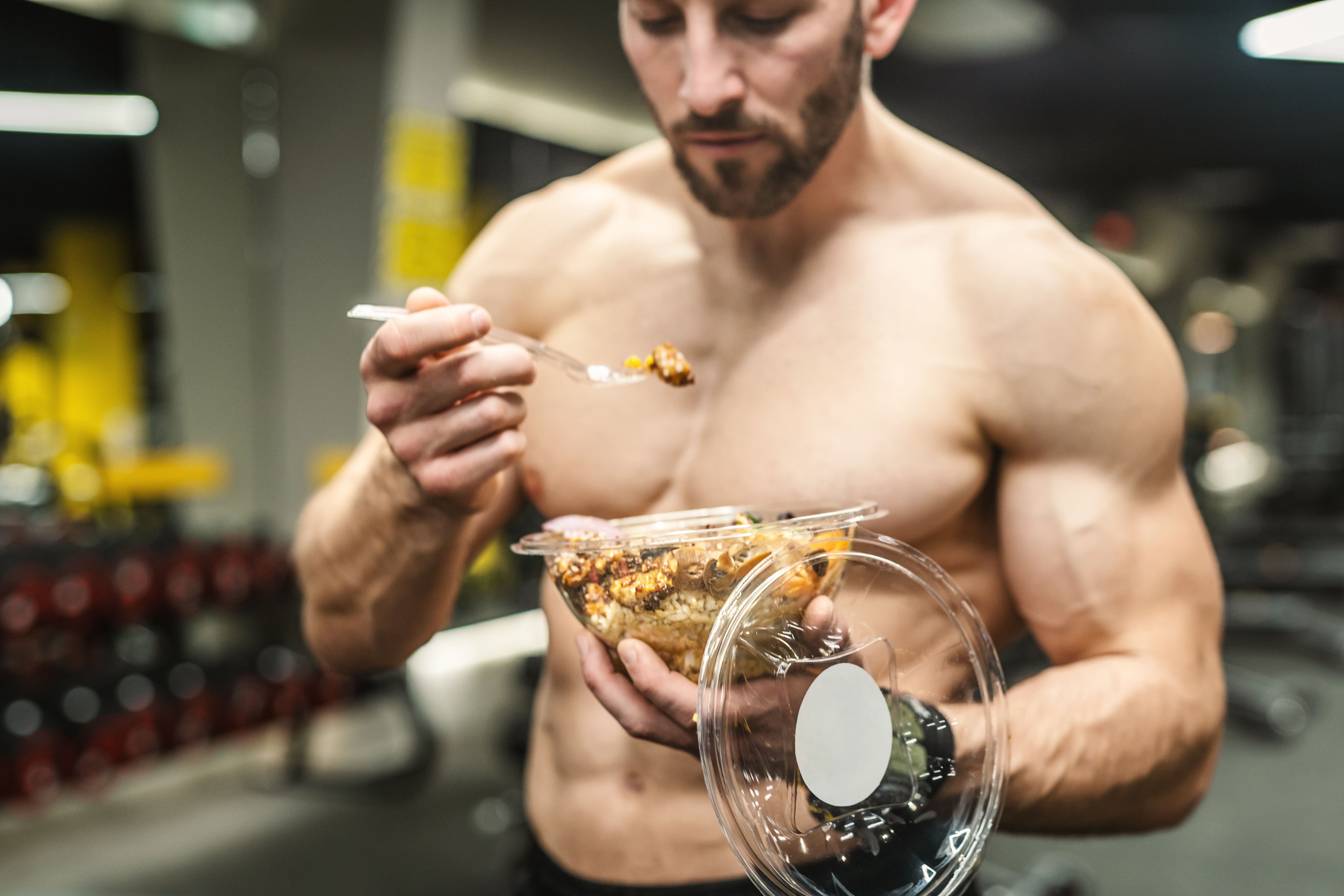 Powerful athletic man with great physique eating a healthy salad. Mockup your brand Powerful athletic man with great physique eating a healthy salad. Mockup your brand