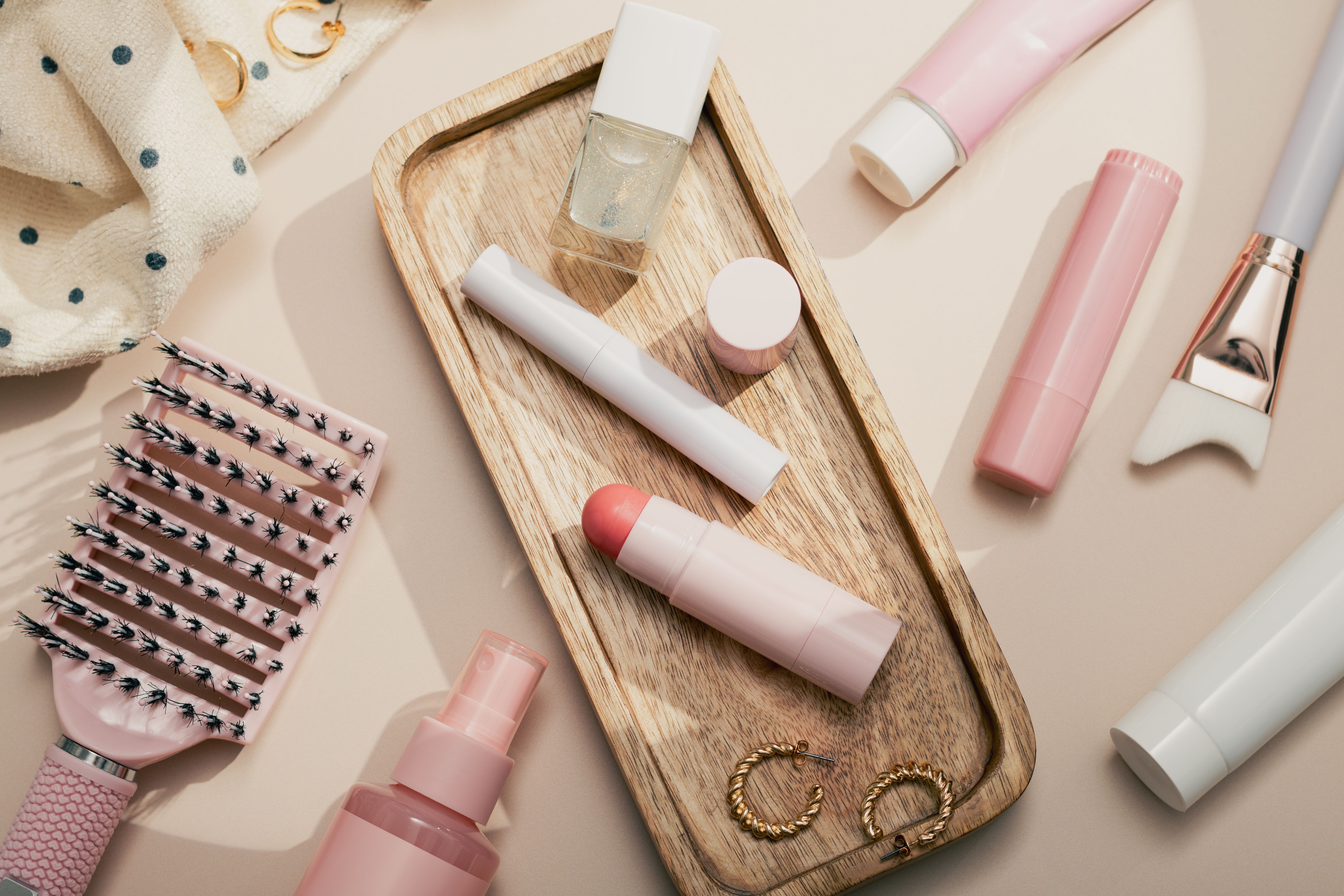 Beauty products background flat lay with skincare, haircare and makeup items on beige