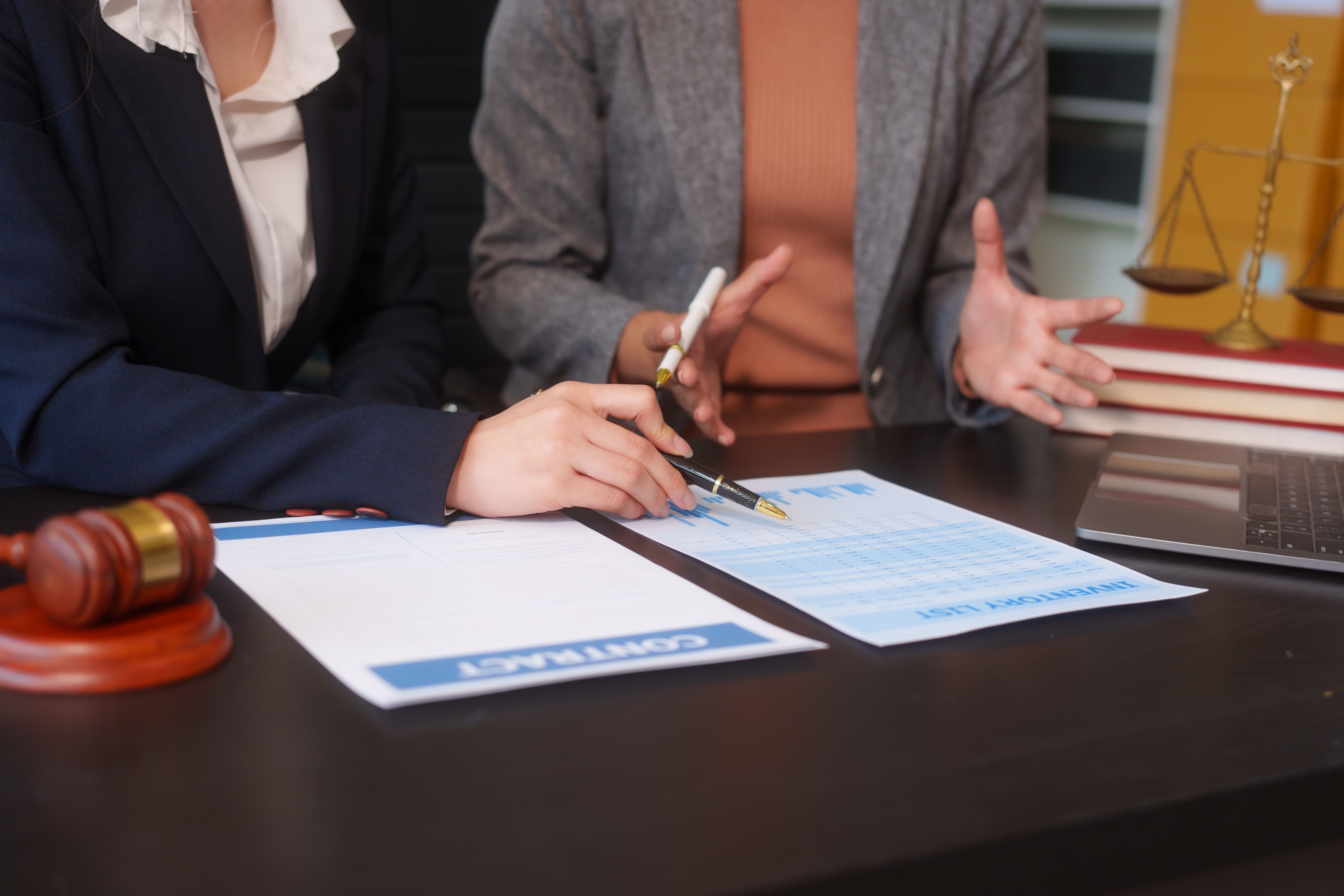 Close-up of two female lawyers hands working at desk, handling legal documents, drafting contracts and preparing for business meetings, specializing in legal and corporate legal services