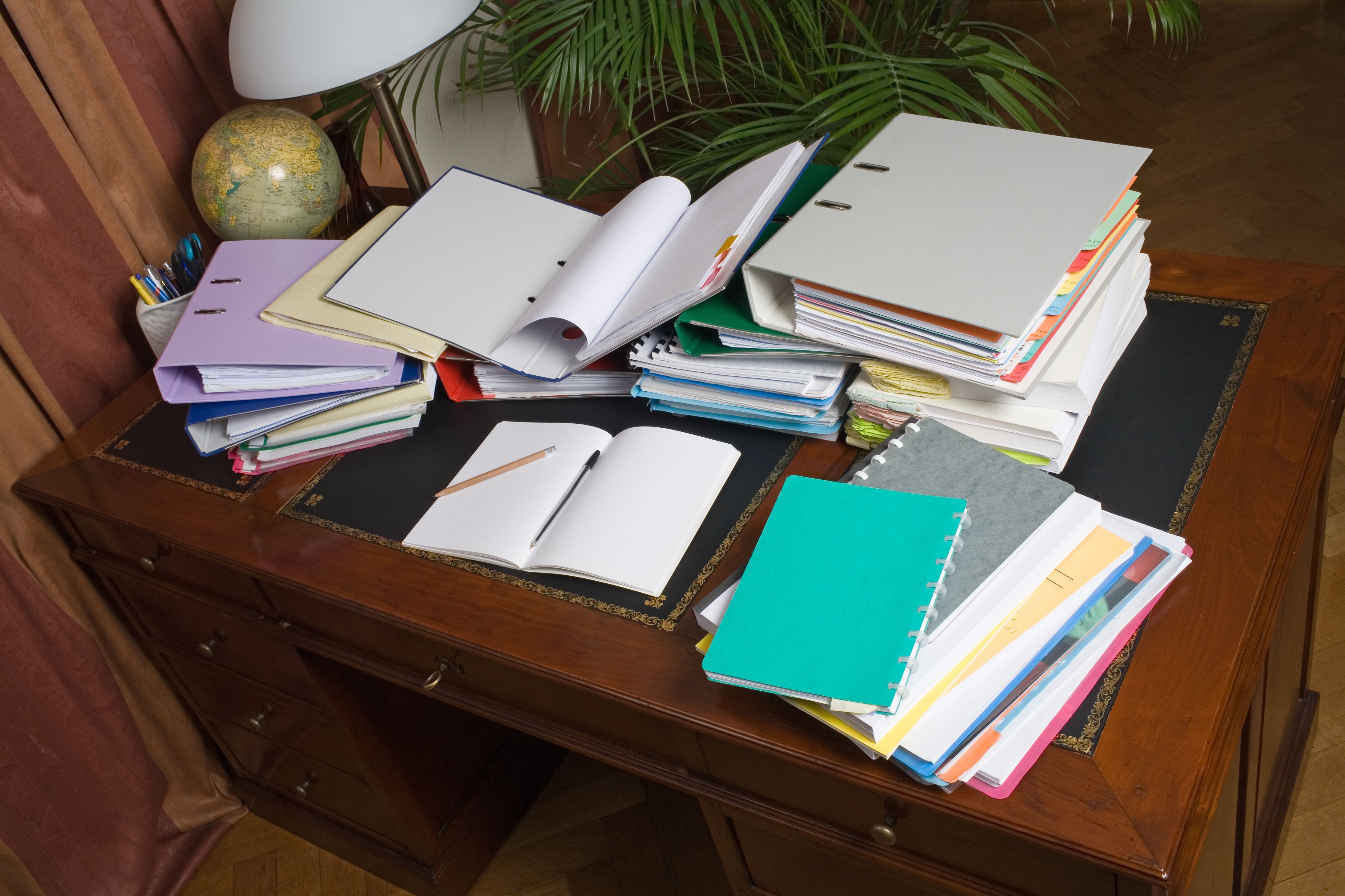 Desk, cluttered with binders and paper Desk, cluttered with binders and paper