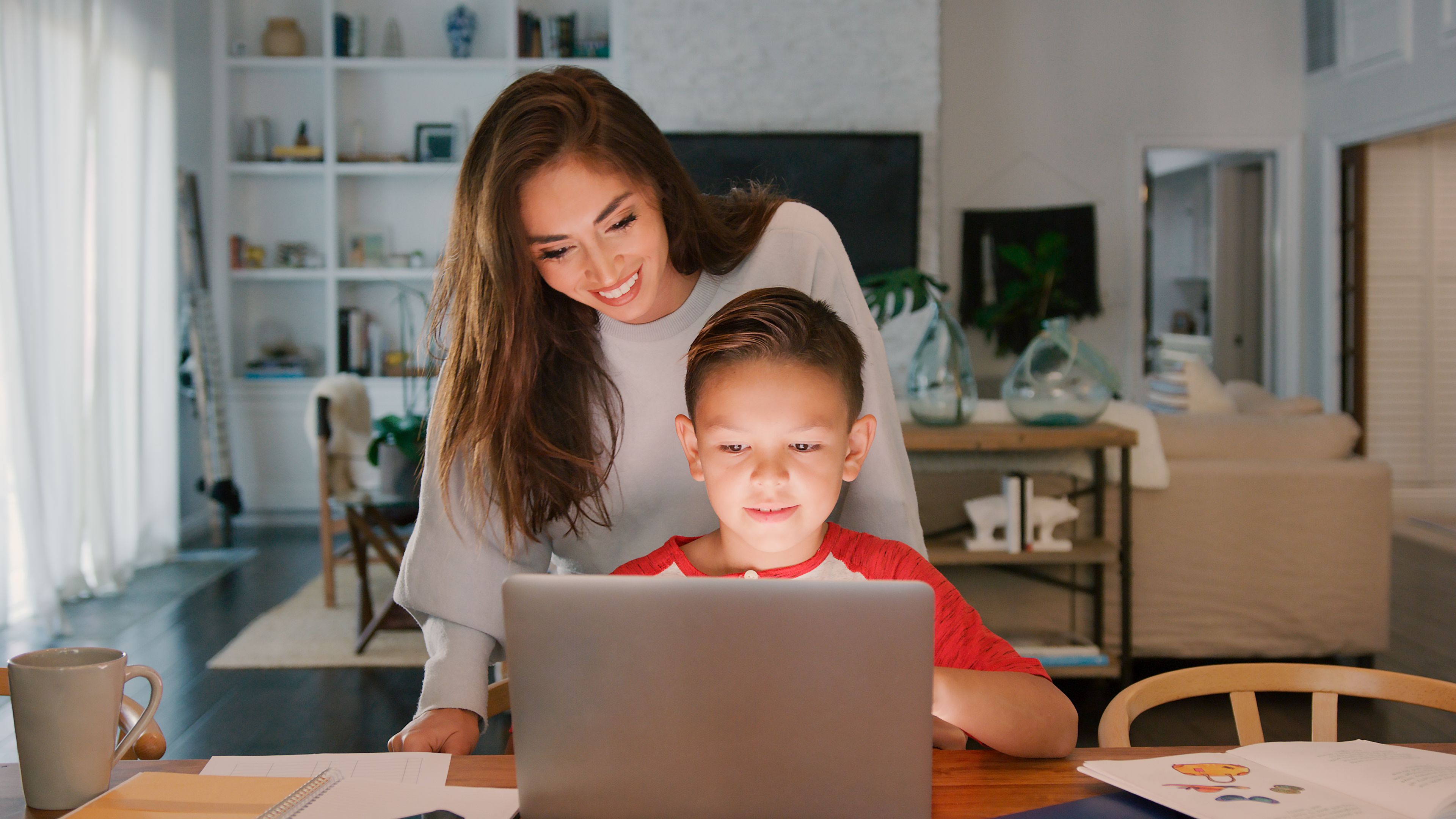 Mother Helping Son Studying Using Laptop At Home Together