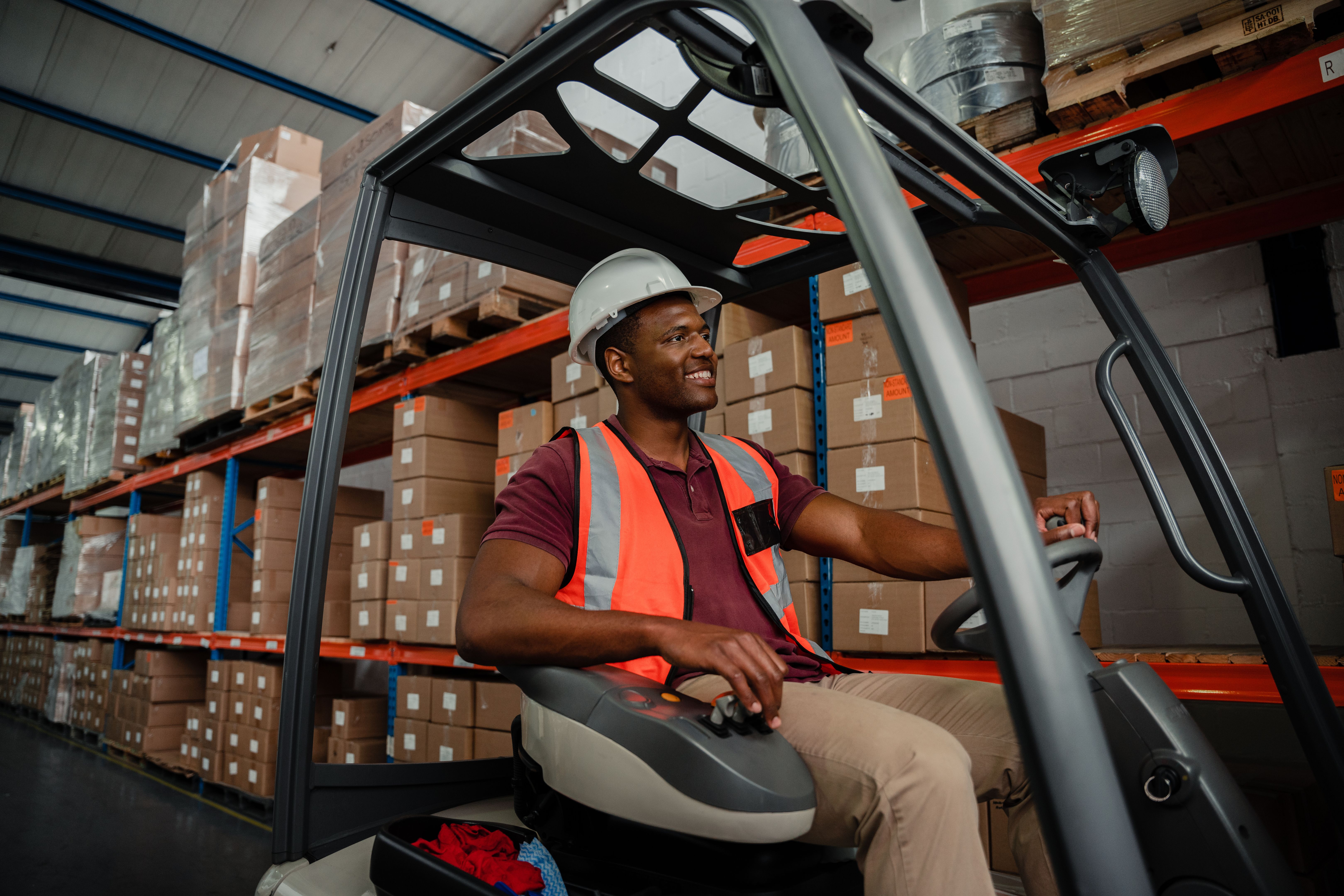 Mixed race worker driving forklift around warehouse while searching for parcels Mixed race worker driving forklift around warehouse while searching for parcels
