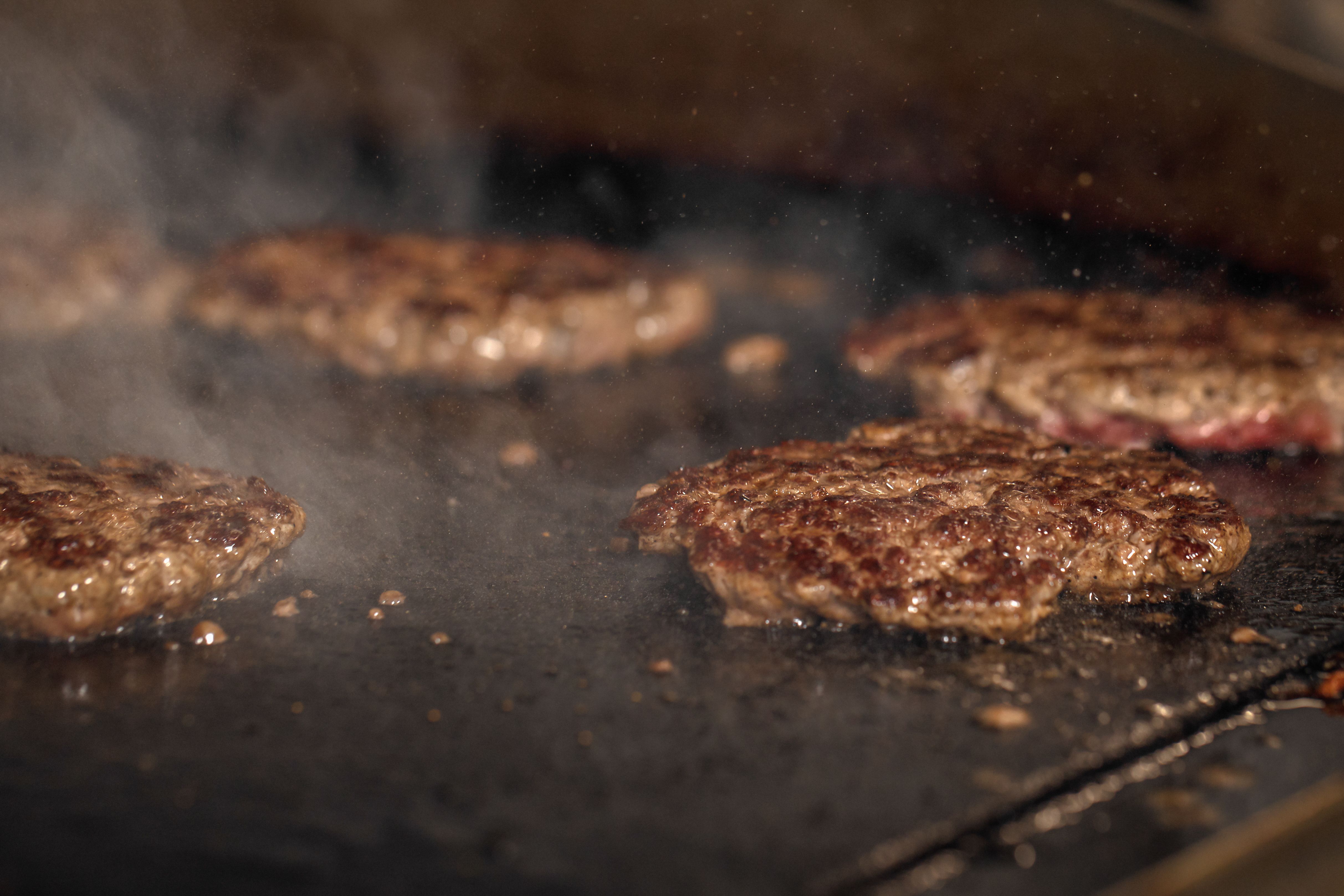 Process of cooking cheeseburgers on the grill.  Close up beef meat burgers for hamburger