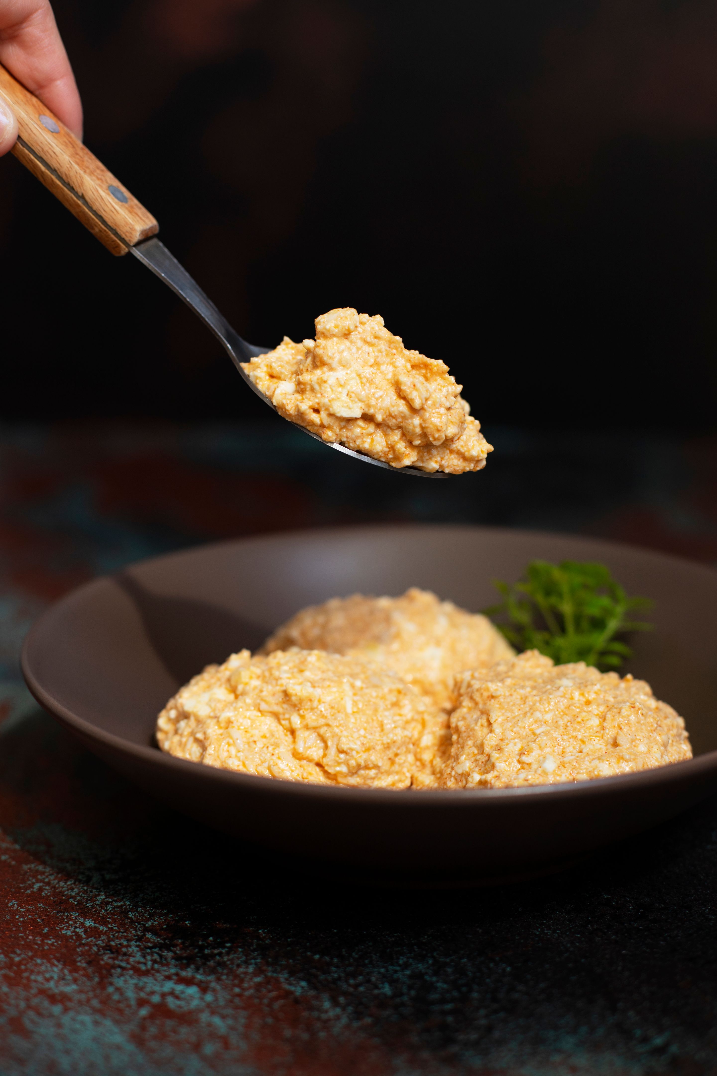 Serbian salad called Urnebes of cheese and chili peppers, paprika powder, chopped peppers and dry peppers (aleva). Traditional Serbian appetizer. Spoon with salad. Serbian cuisine. Closeup. Copy space