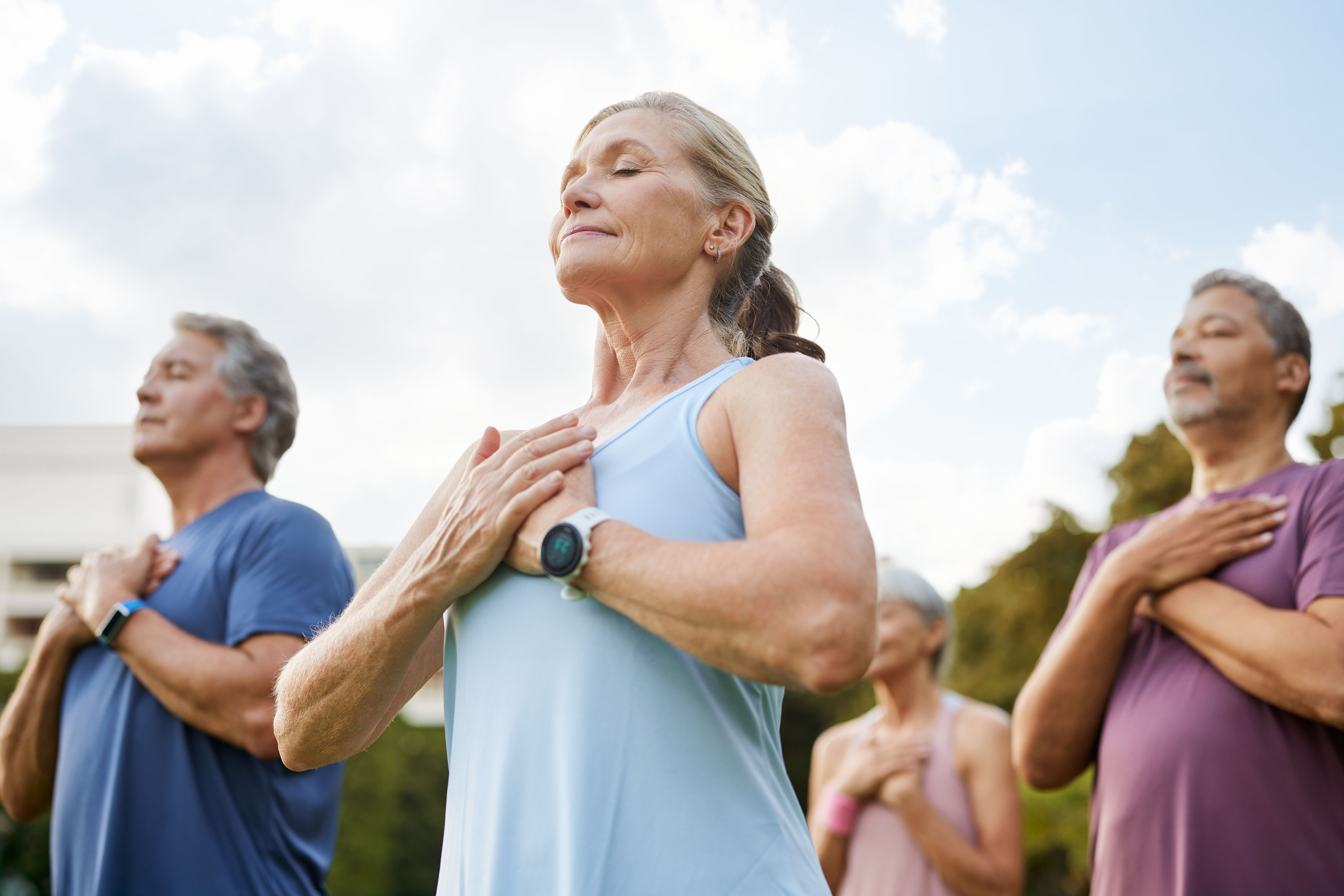 Personas multiétnicas maduras activas que practican la meditación en el parque