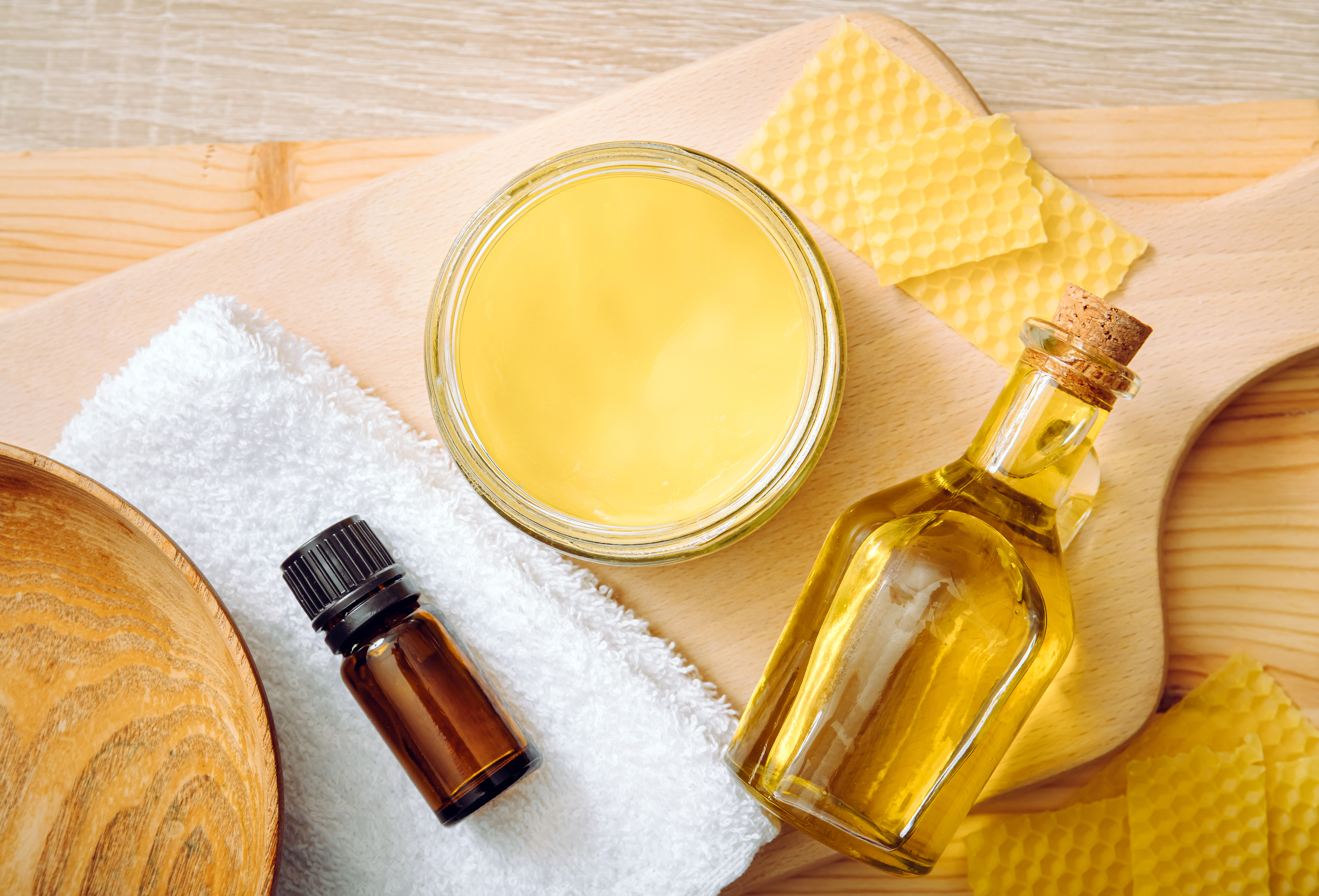 Homemade beeswax wood treatment polish, restore natural wood furniture, plates, cutting boards. Beeswax, olive oil and essential oil, soft cloth and mixture in glass jar.