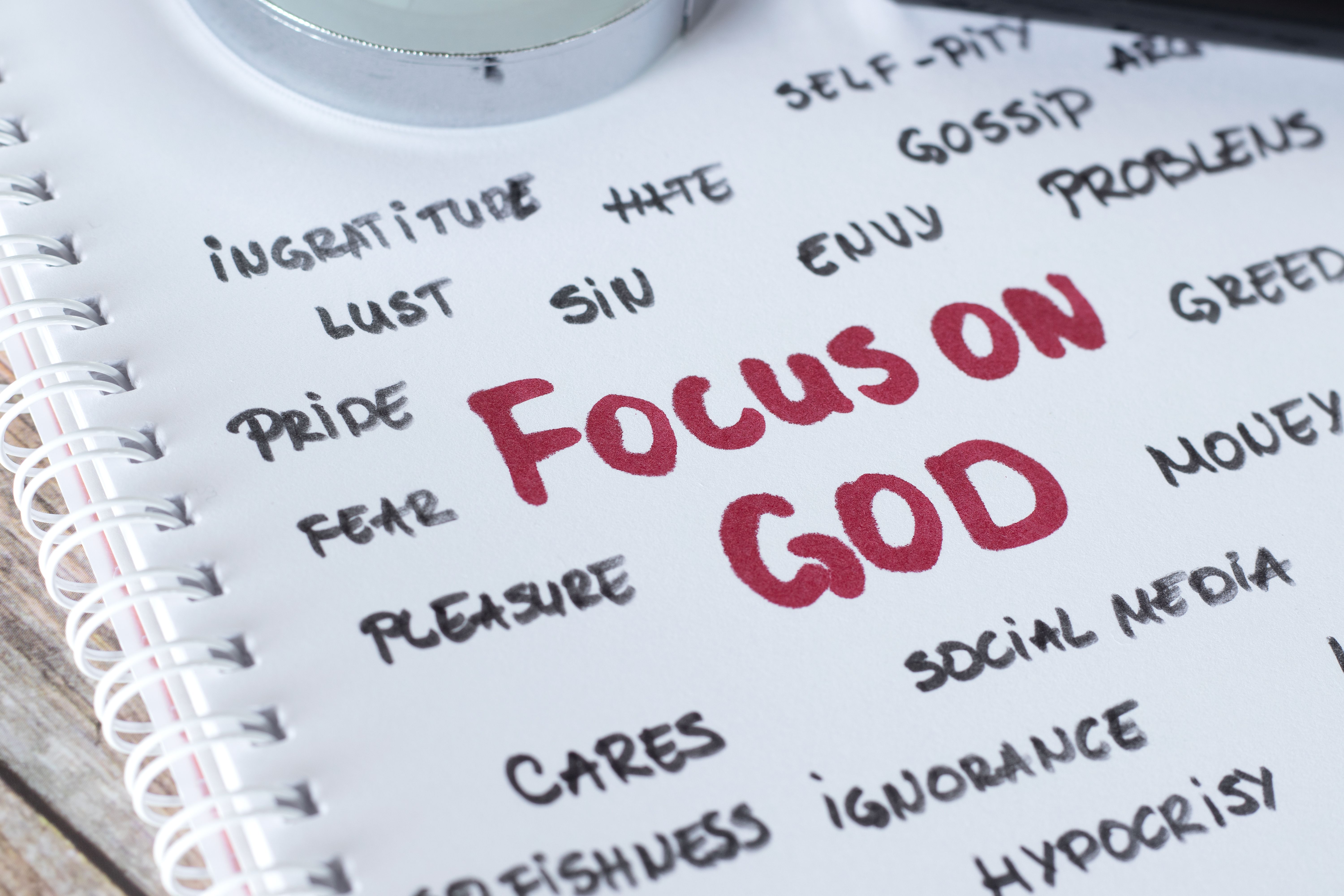 Focus on God, handwritten words in notebook with magnifying glass