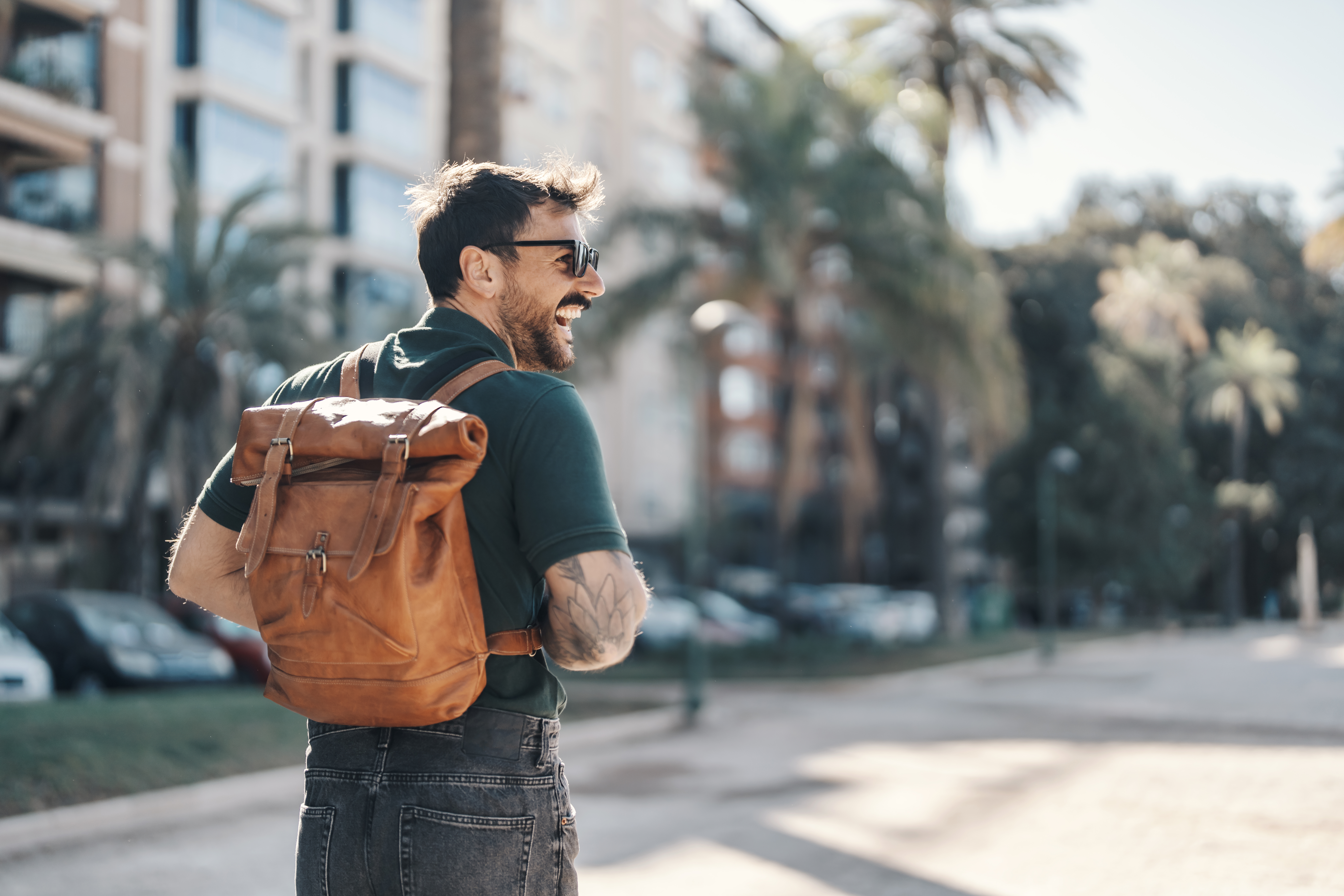 Rear view of a young hipster with a backpack walking on a city street downtown. Rear view of a young hipster with a backpack walking on a city street downtown.