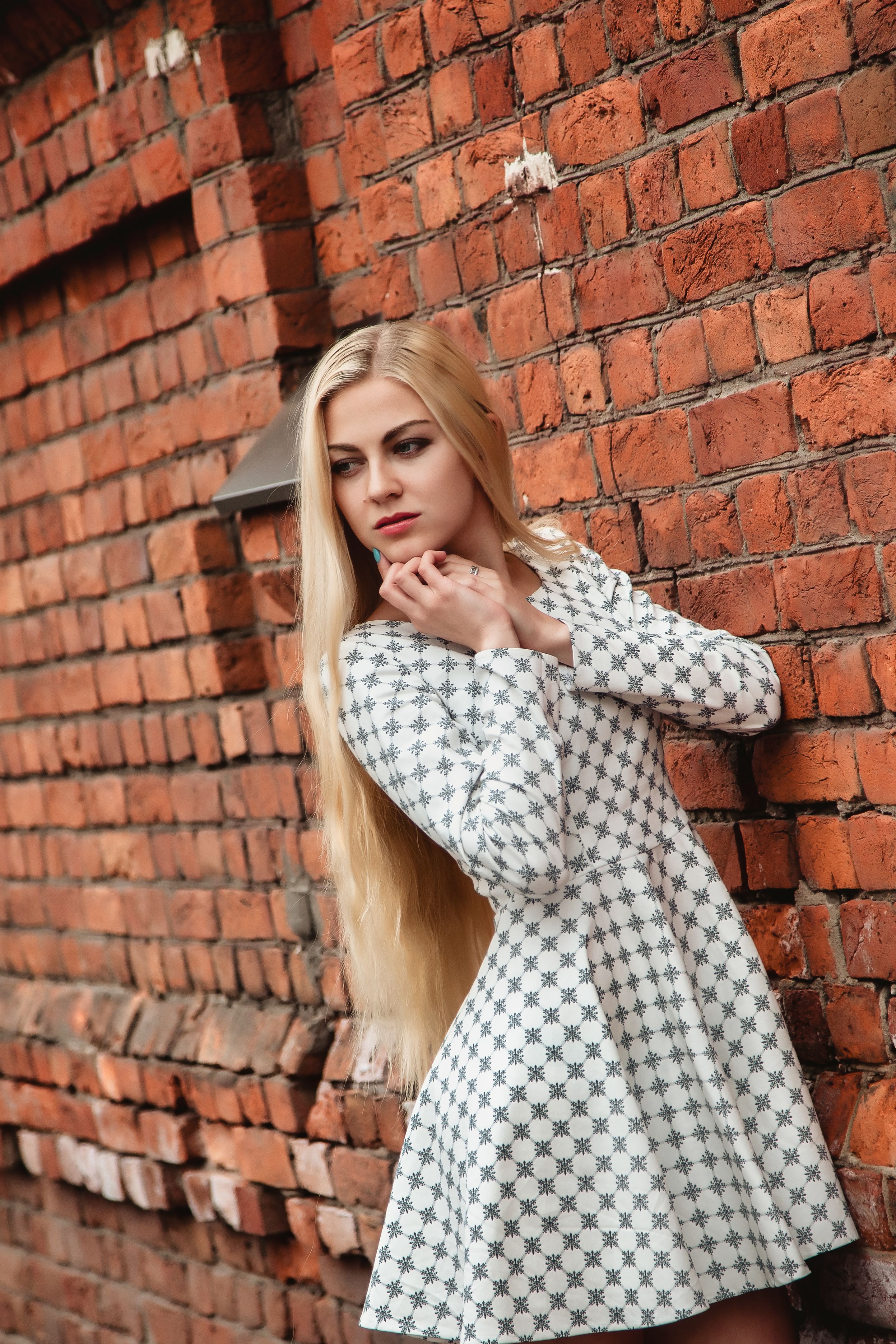 Portrait jewish young blonde woman model with long hair at brick wall background, thinking and looking away. Pretty lady in white dress posing outdoors. Concept positive emotion, fashion. Copy space Portrait jewish young blonde woman model with long hair at brick wall background, thinking and looking away. Pretty lady in white dress posing outdoors. Concept positive emotion, fashion. Copy space