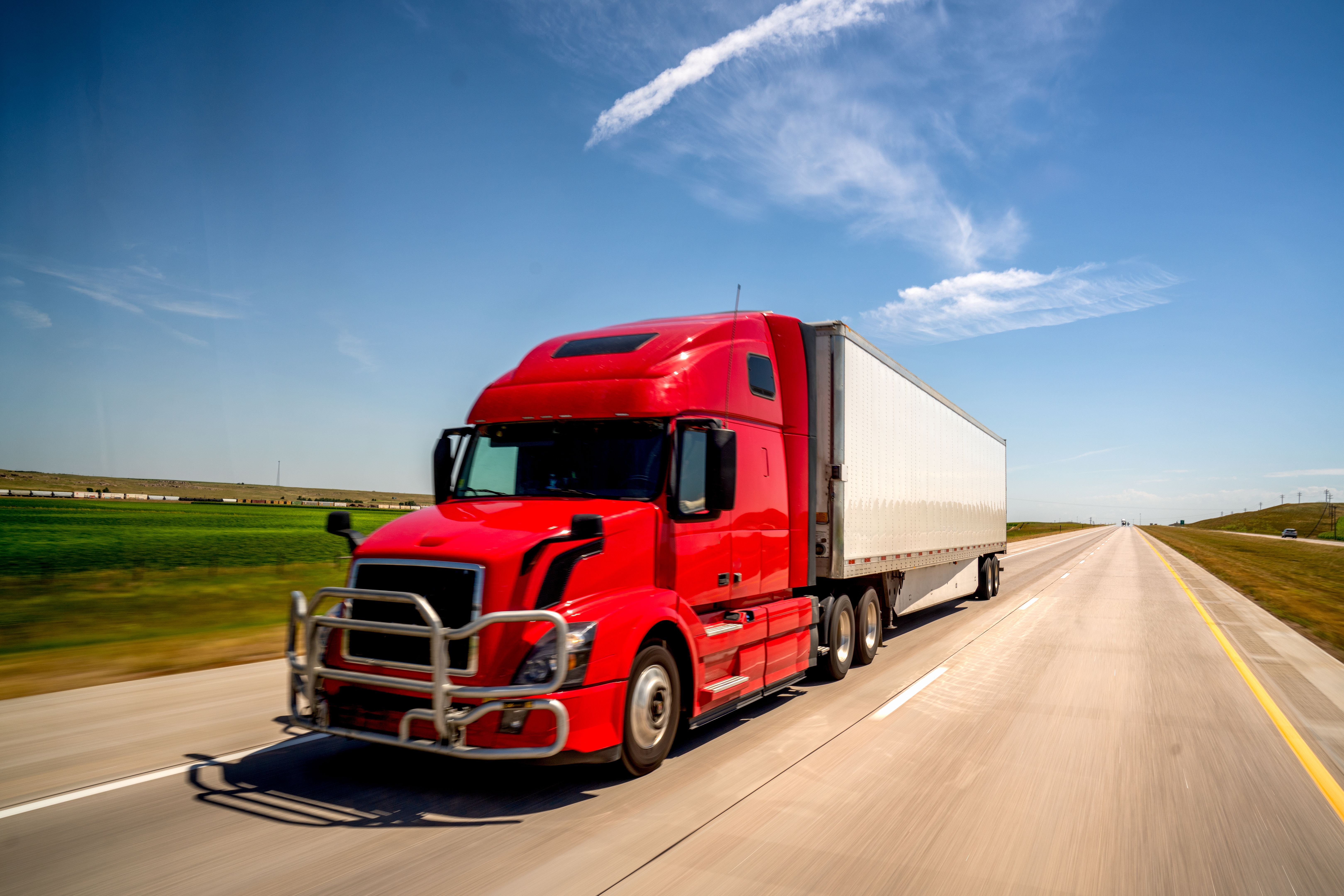 A Cloes-up View Of A Long Haul Semi Truck Speeding Down a Four Lane Highway