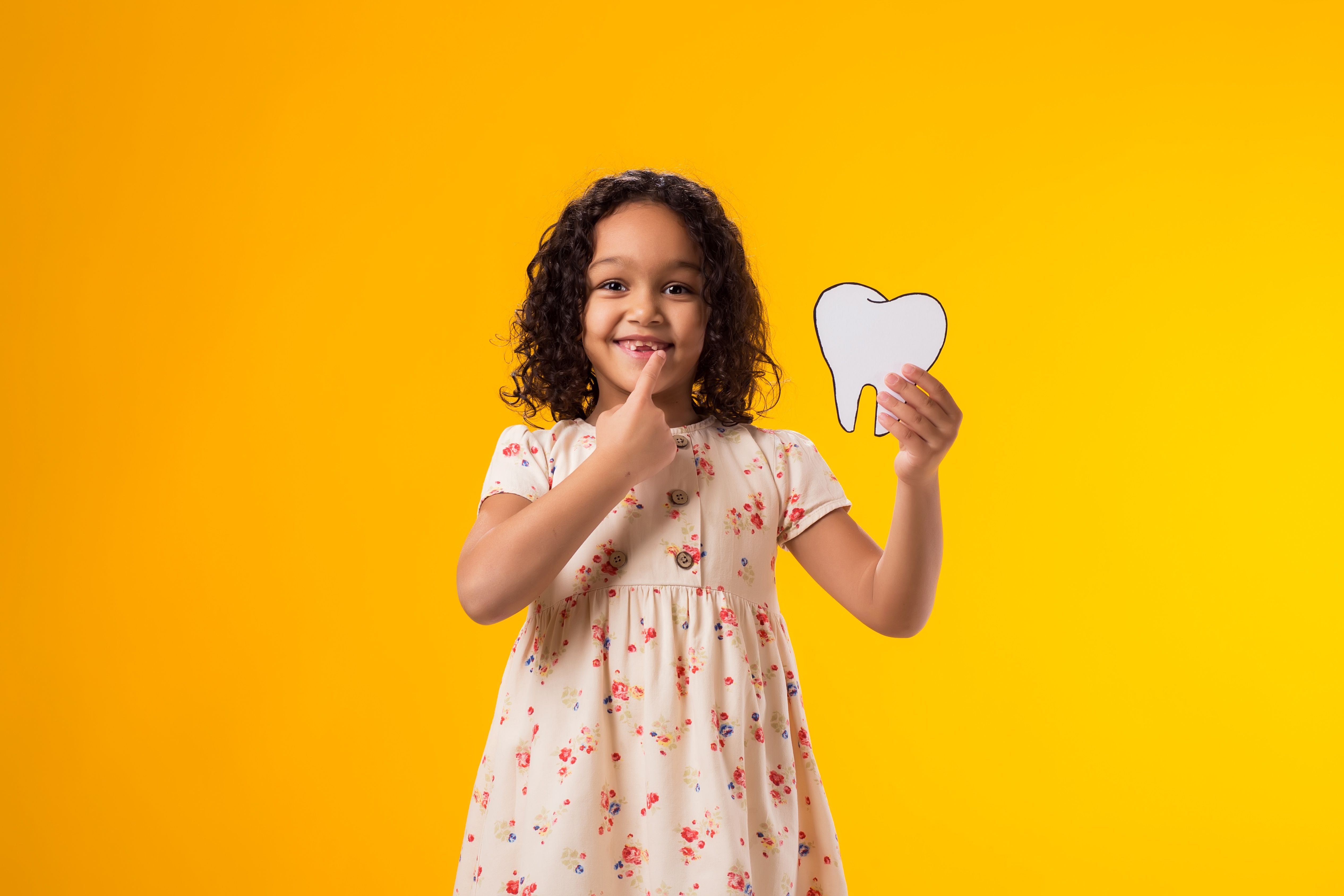 Niña sujetando un diente de papel. Concepto salud dental. Niña sujetando un diente de papel. Concepto salud dental.