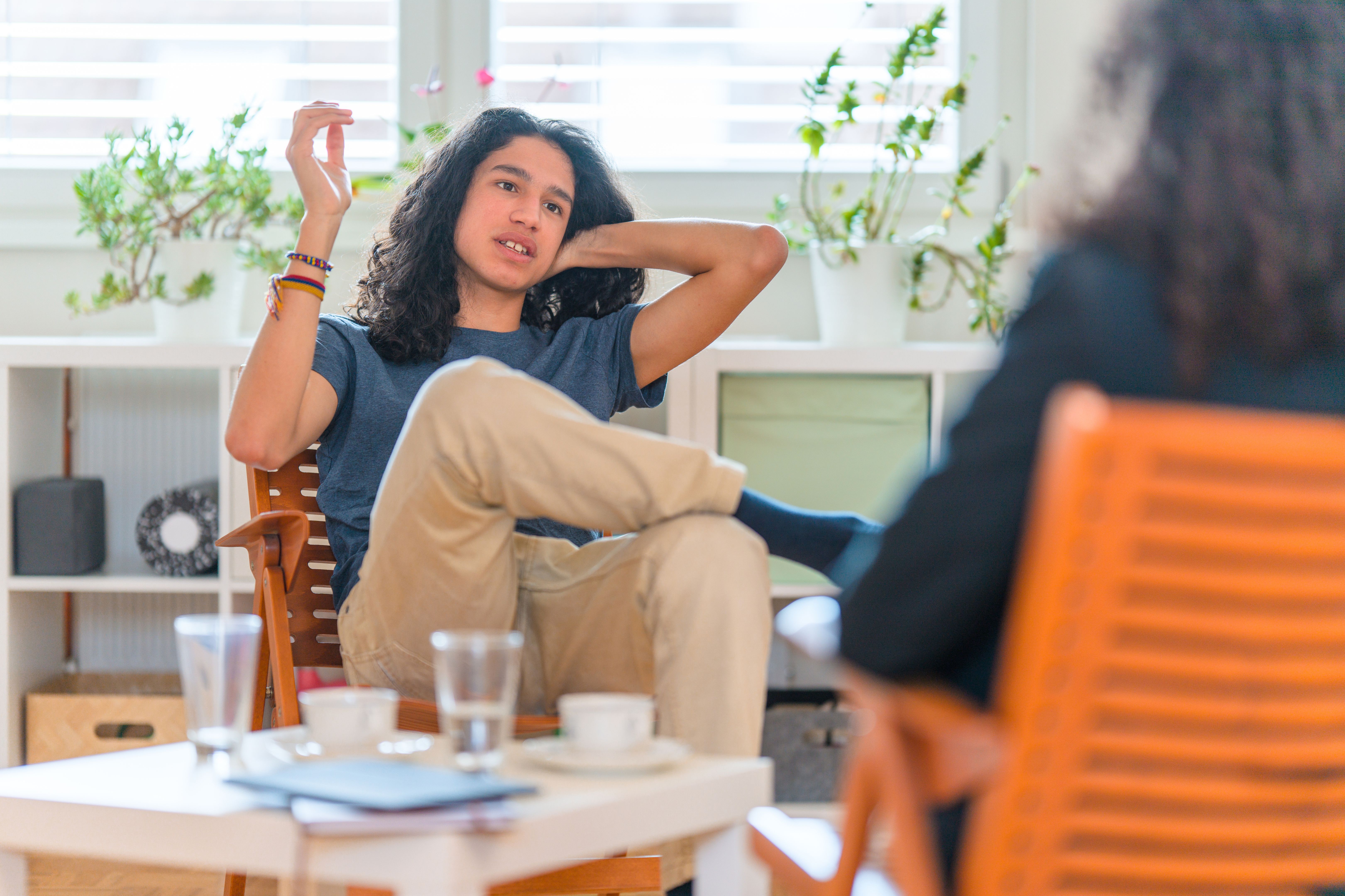 Young Hispanic Male Patient Listening To Female Psychotherapist in her Office