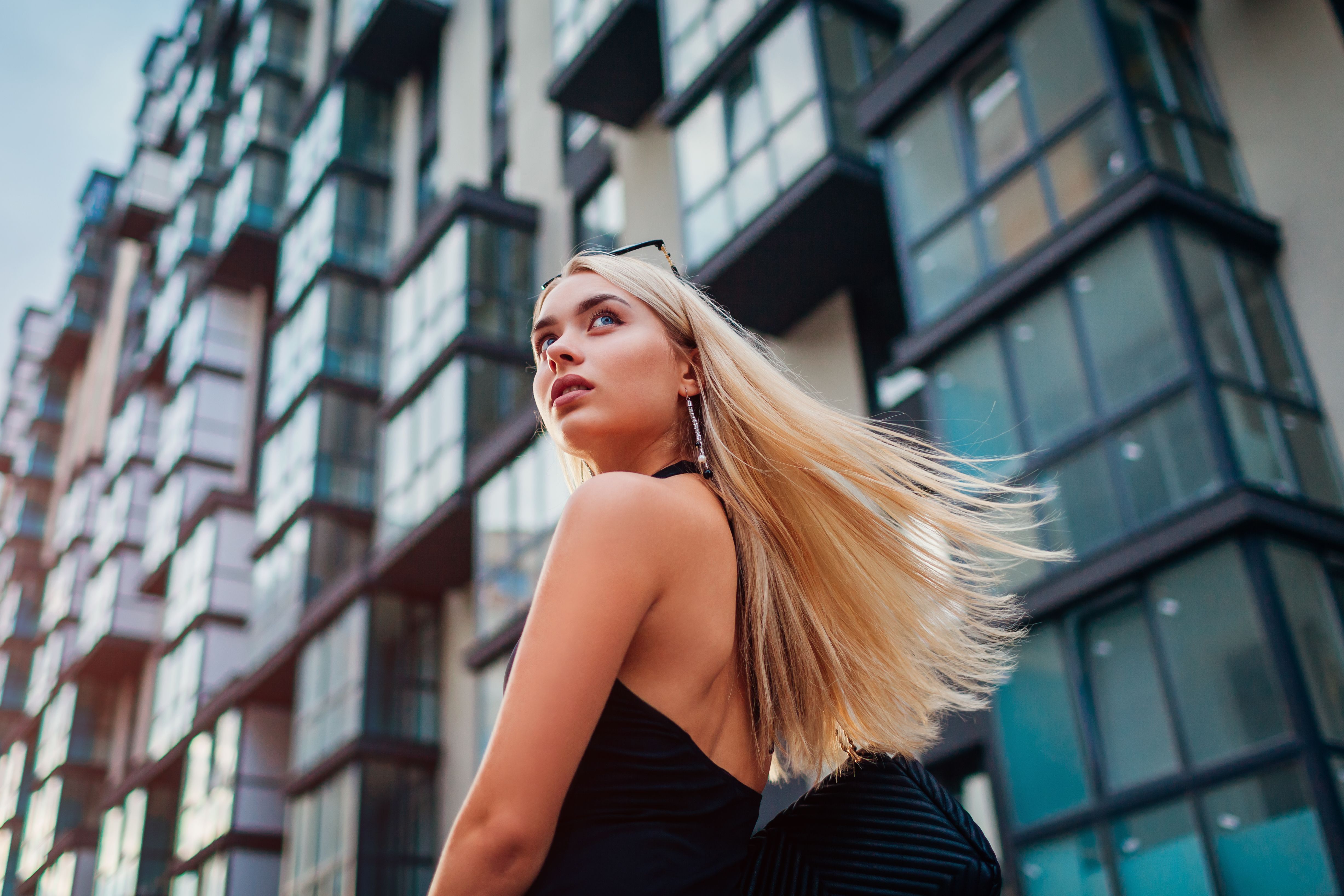 Young blonde businesswoman walking along modern business center in city. Portrait of stylish successful woman Young blonde businesswoman walking along modern business center in city. Portrait of stylish successful woman