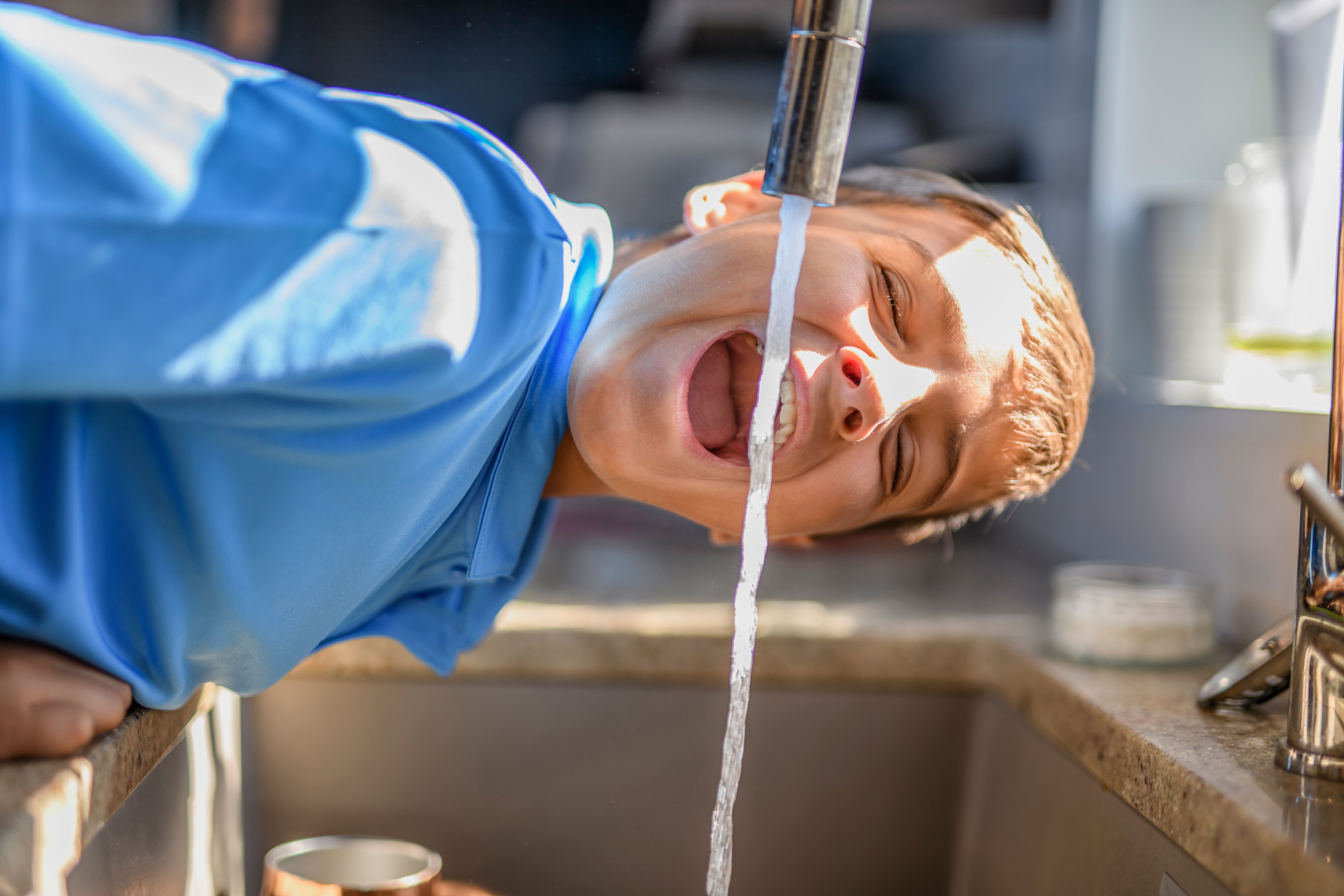 Boy drinking water direct from the faucet