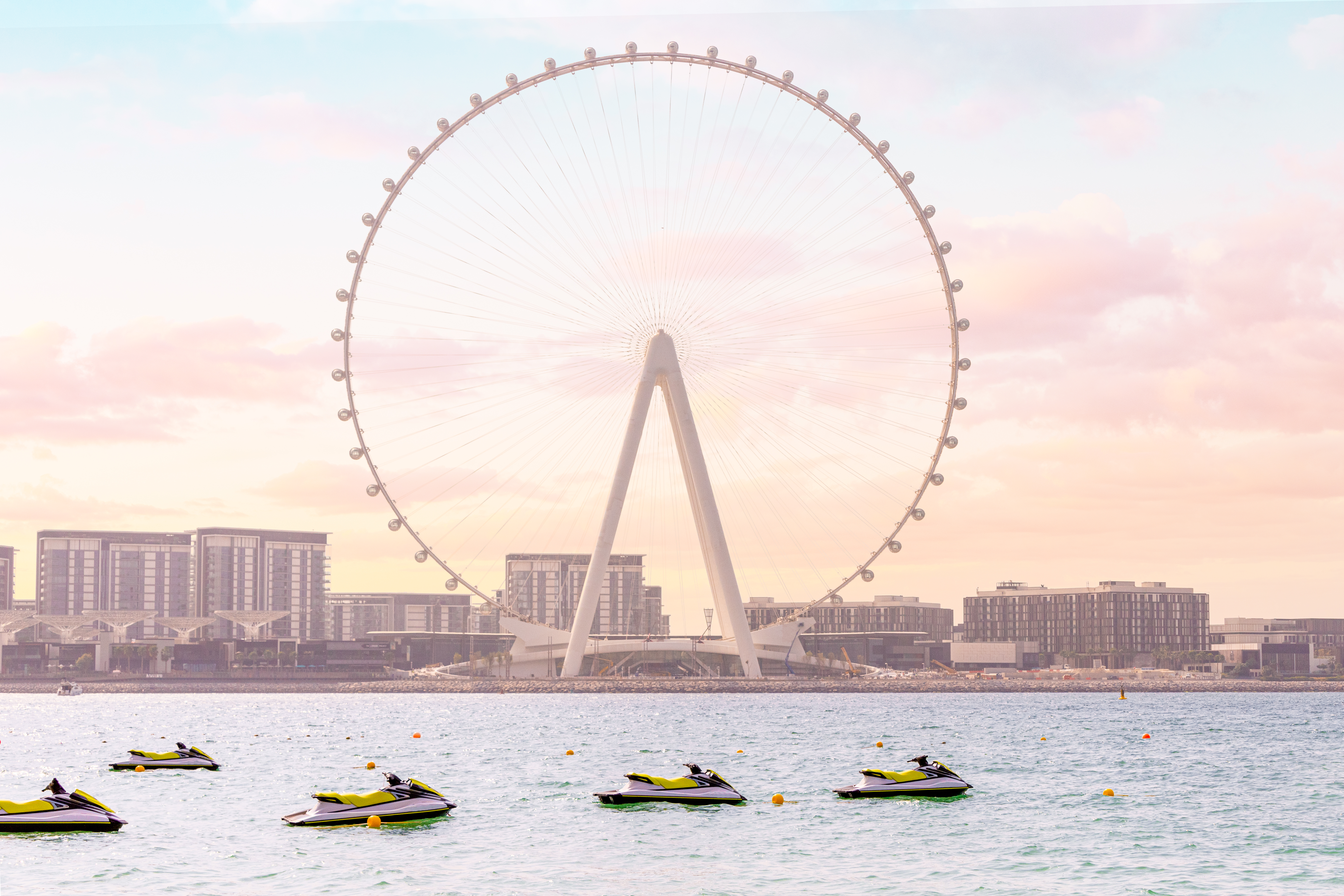 Sea scooters and aquabikes as water sports attractions waiting for vacationers against the backdrop of the famous Ferris wheel Dubai Ain