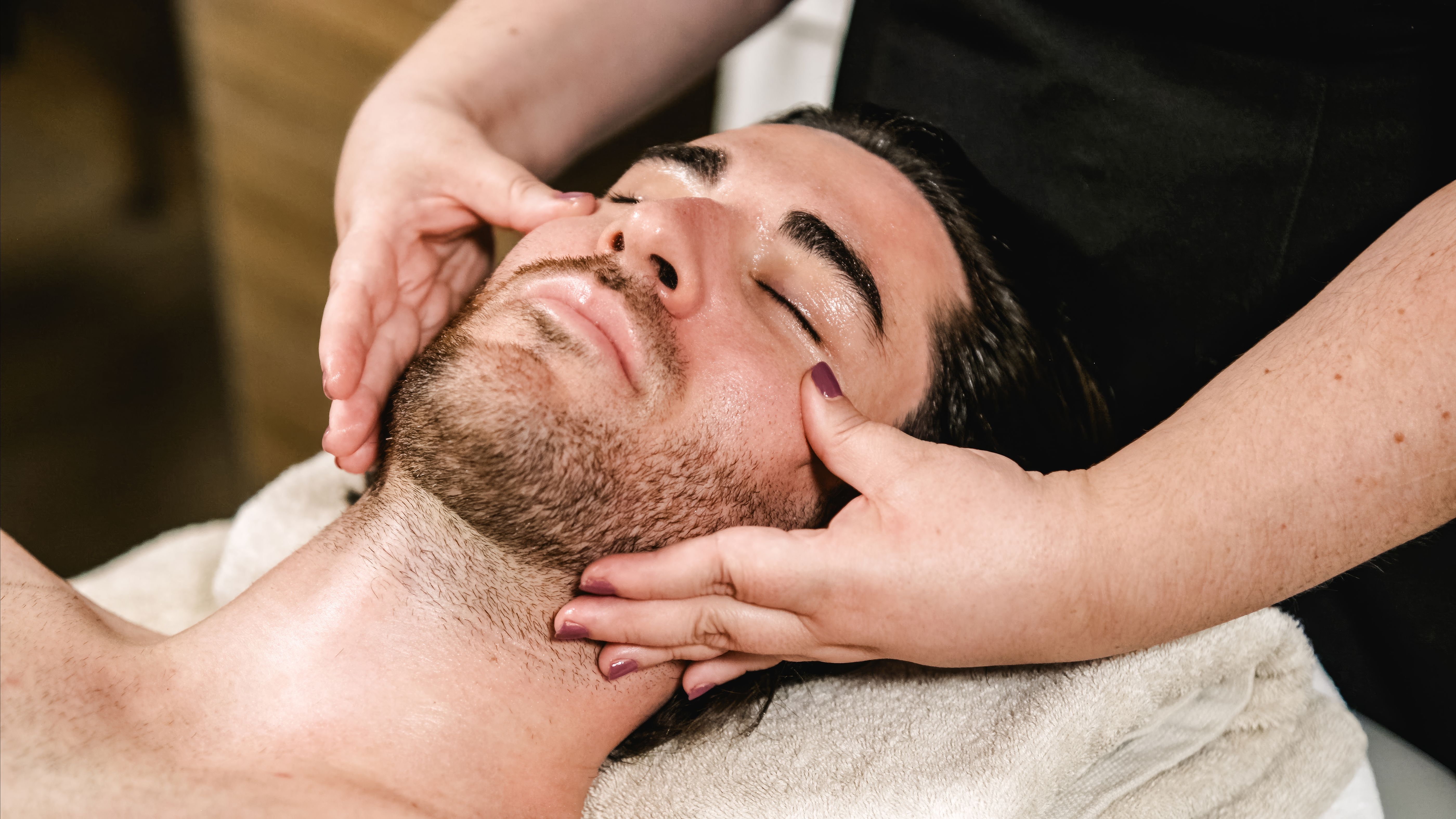 Beautician giving relaxing face massage to male client