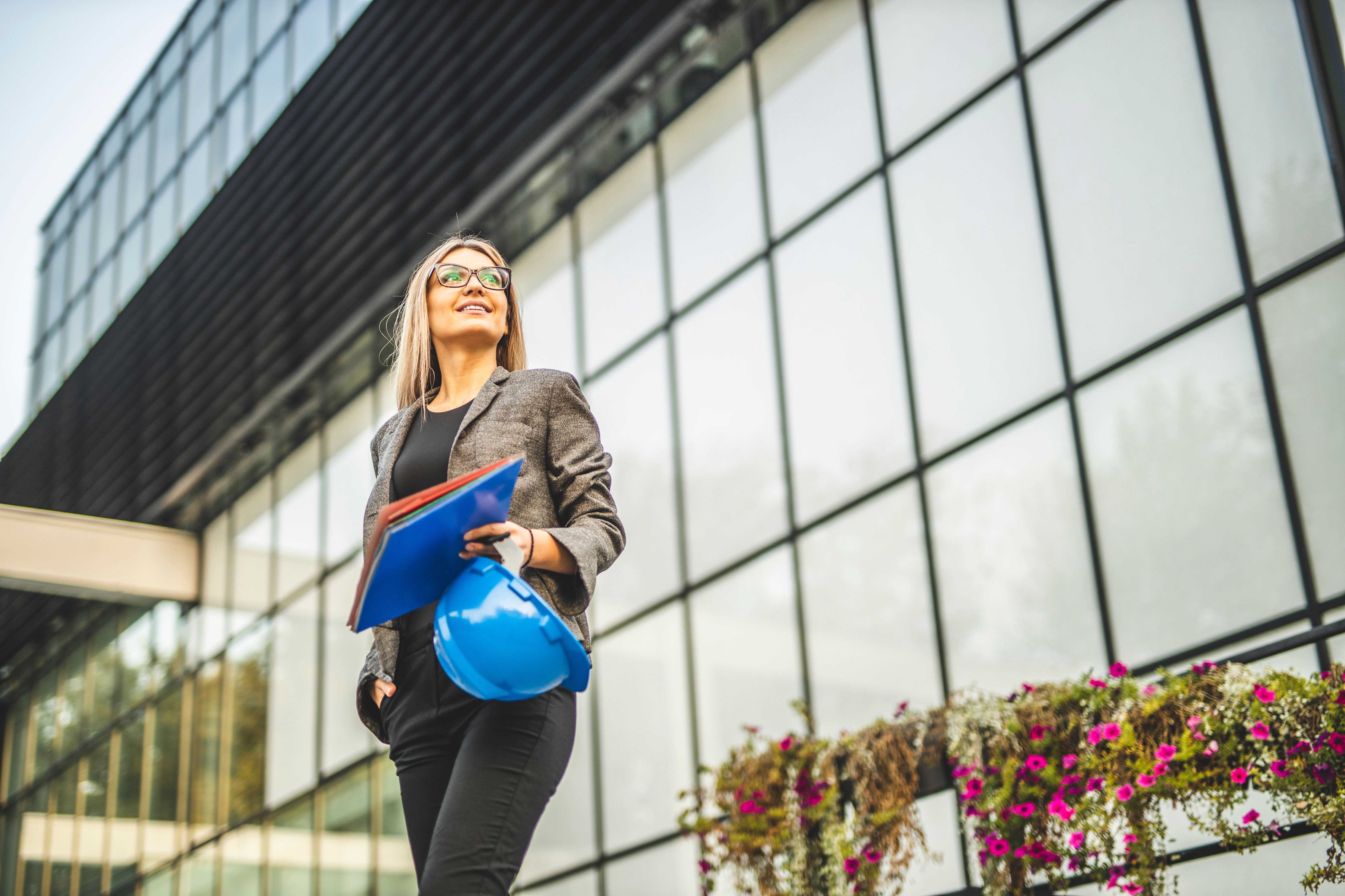 Businesswoman holding document and helmet outdoors Businesswoman holding document and helmet outdoors