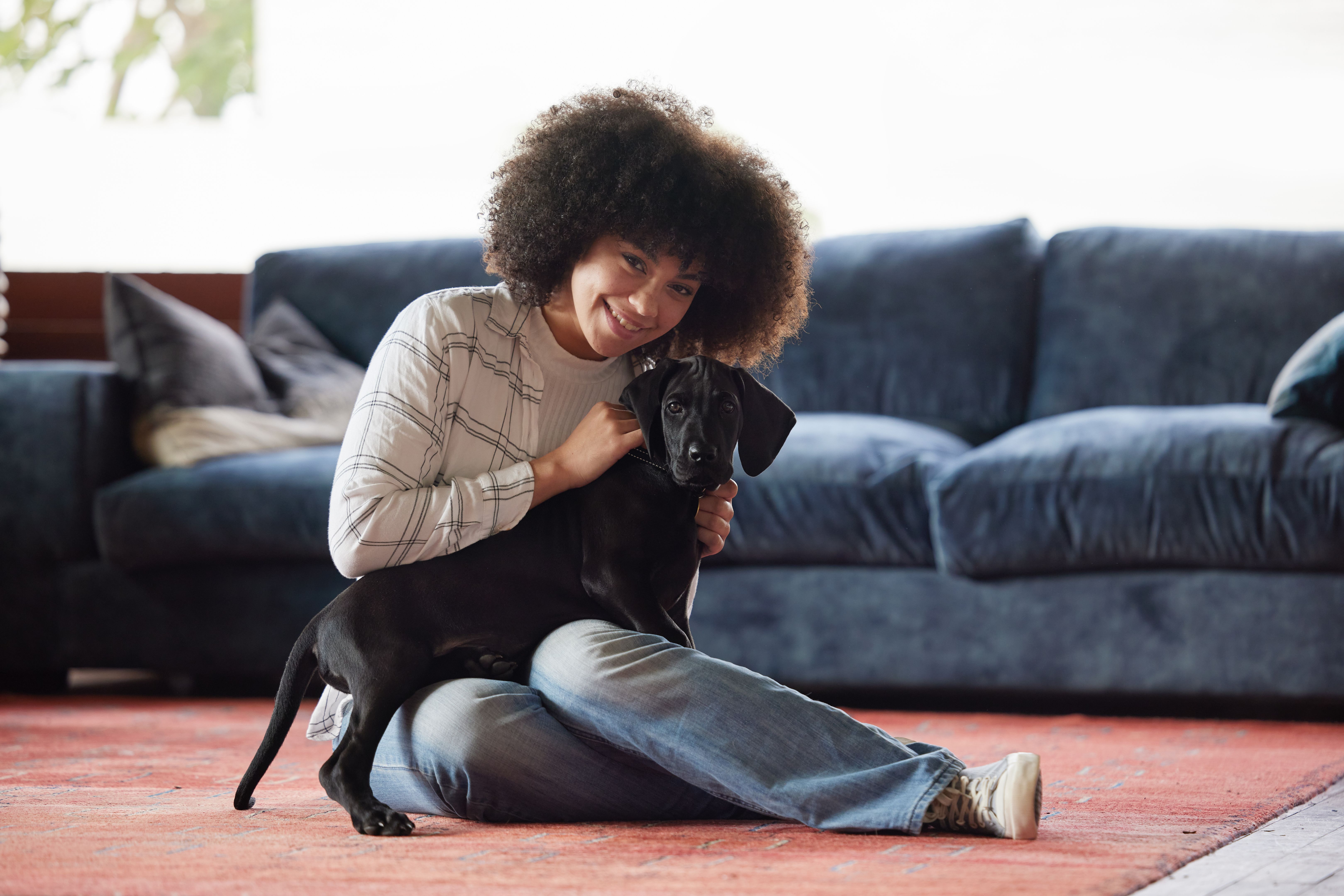 Shot of a young woman playing with her dog at home