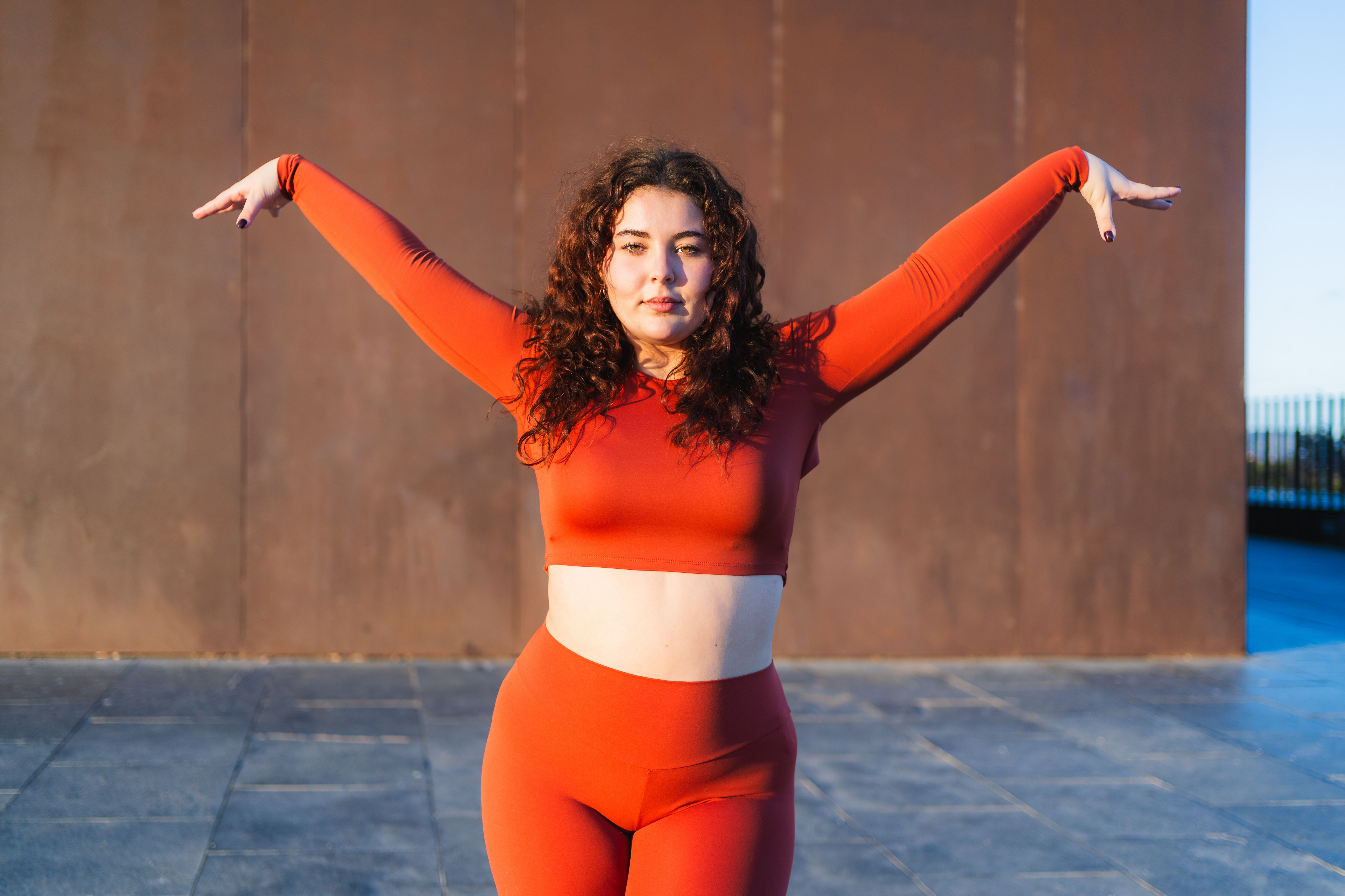 Young plus size dancer performing a choreography outdoors in an urban setting