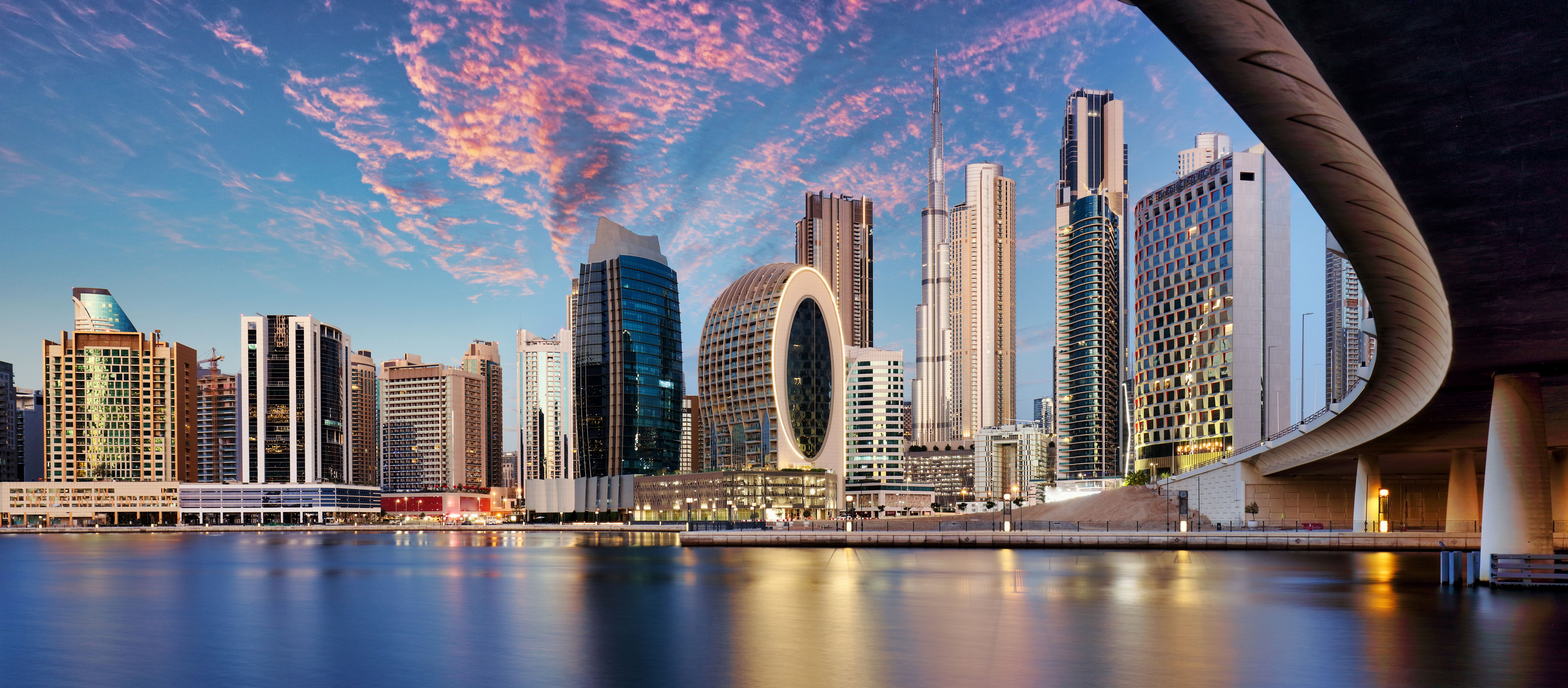 Panorama of Dubai skyline from canal Creek at sunrise and night, UAE