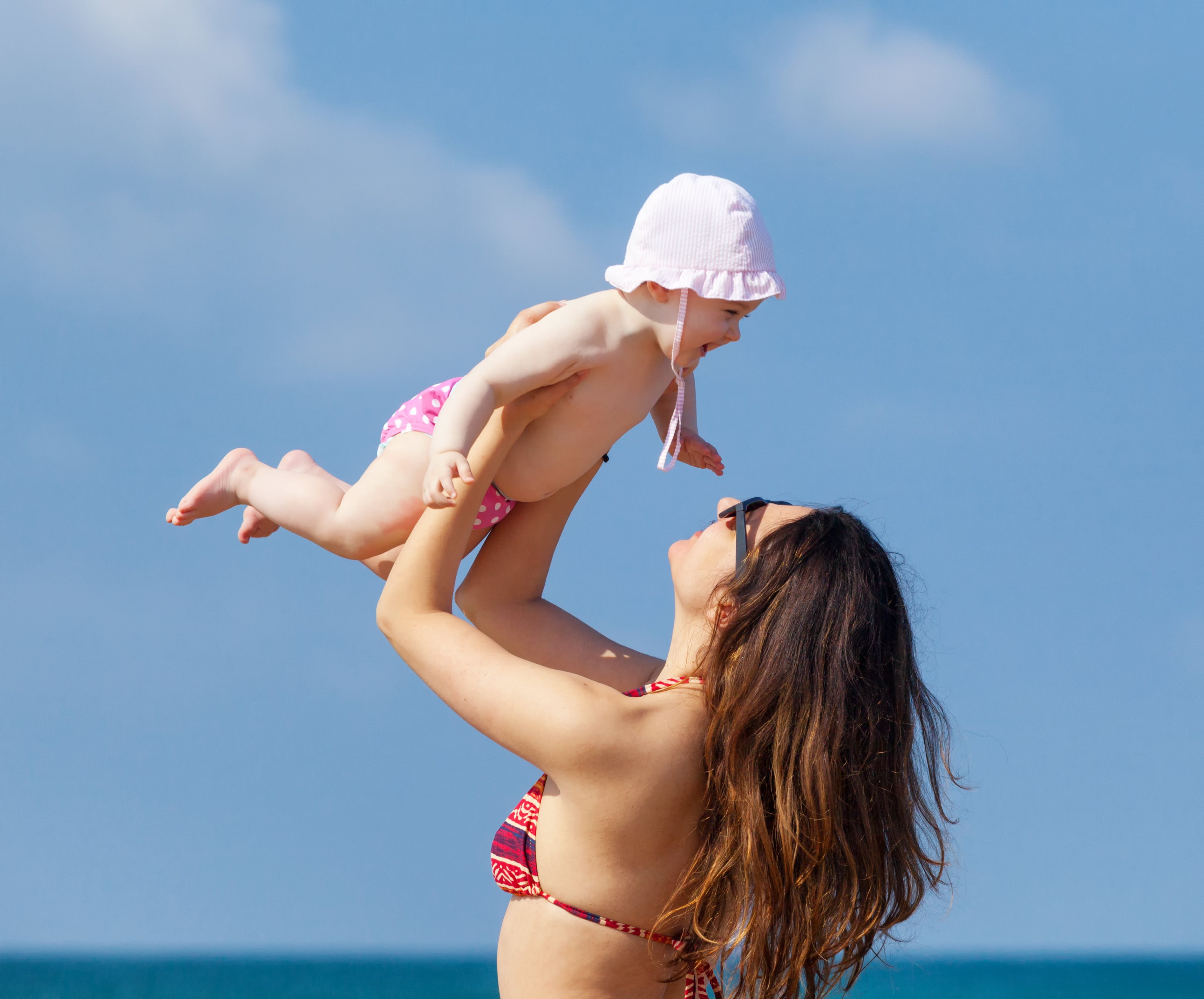 Mother Holding Cute Daughter Against Sky