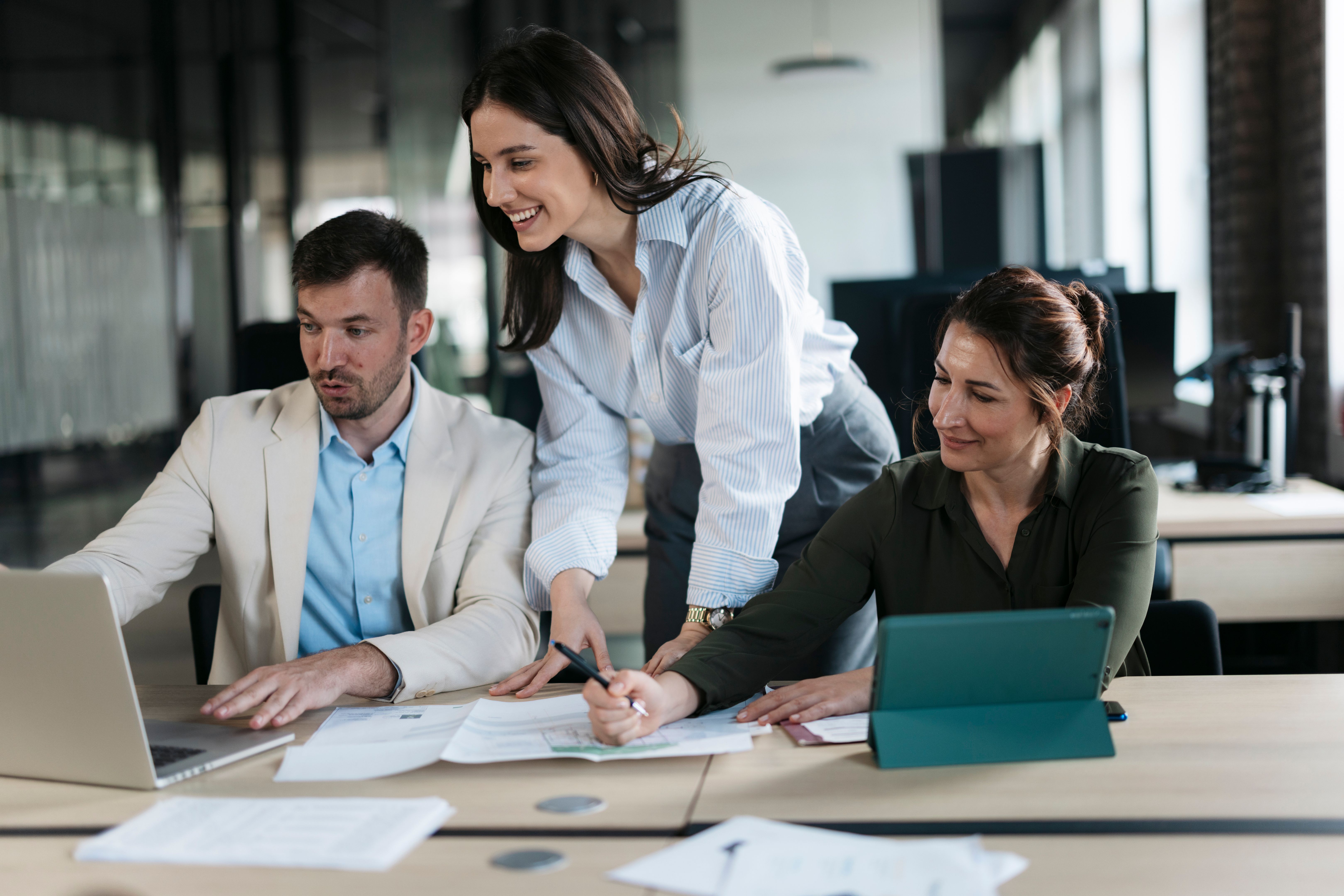 Business team working together on project using laptop and tablet in office