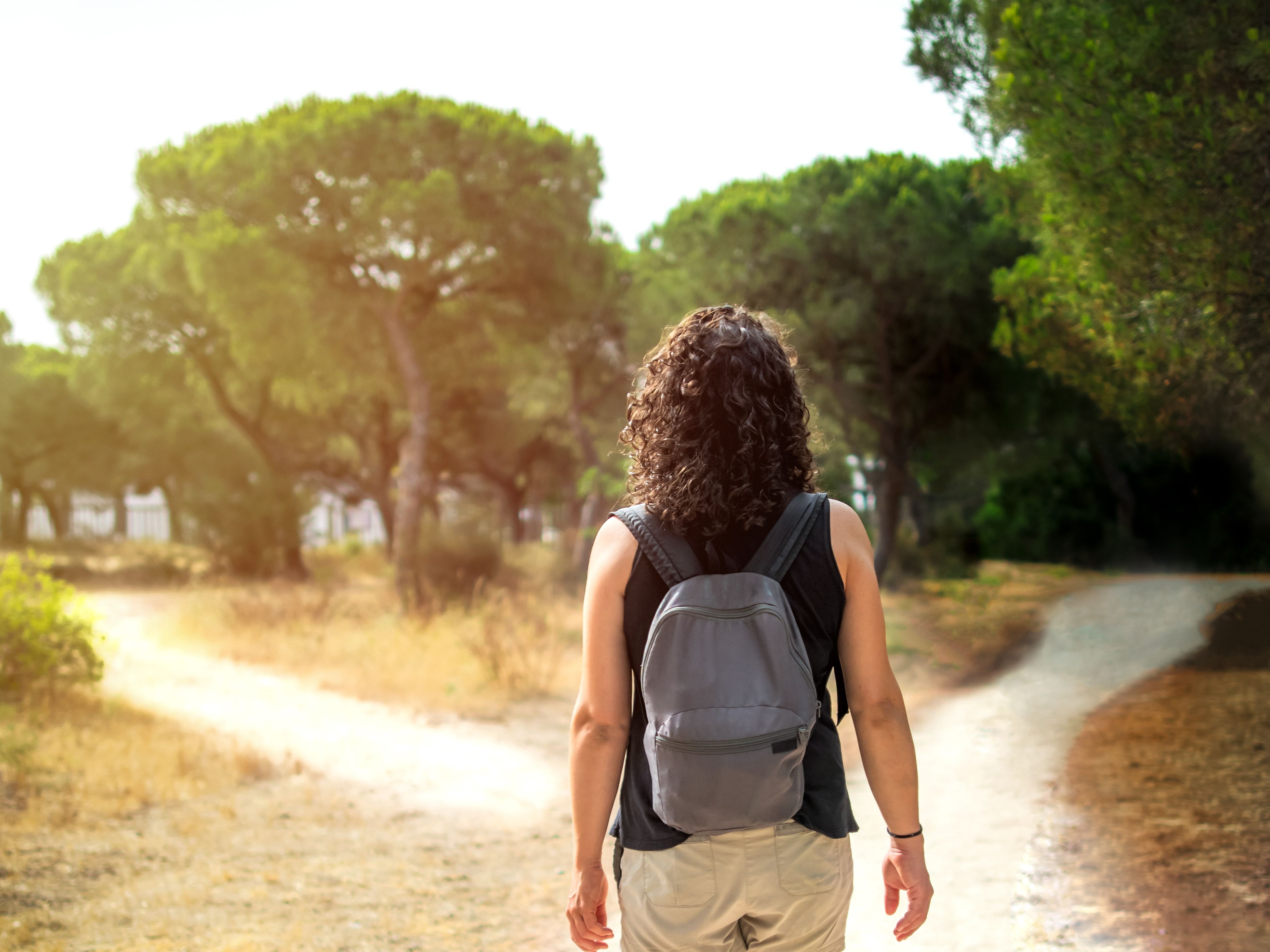 Woman choosing to take a light path or a dark path in a forest. Concept of decision making in life.