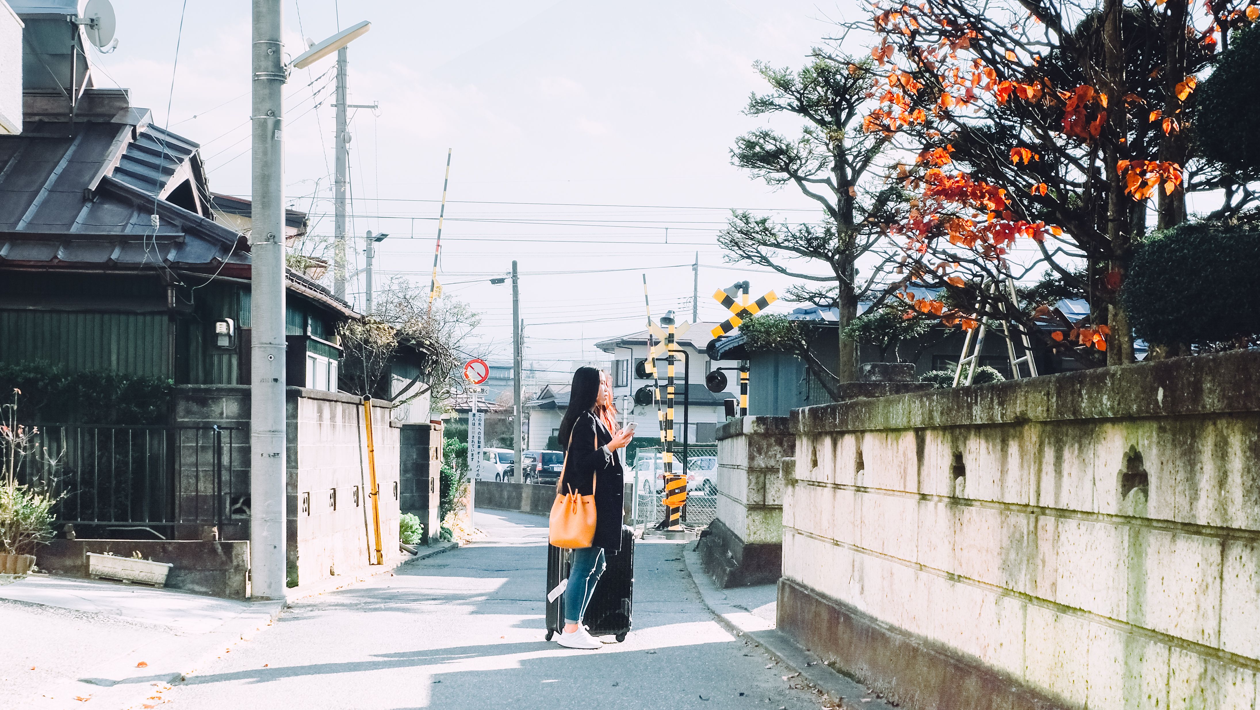 A rare view of young Asian woman traveler is walking with her suitcase on the middle of the street where is located in Fuji-Kawaguchiko, Yamanashi, Japan A rare view of young Asian woman traveler is walking with her suitcase on the middle of the street where is located in Fuji-Kawaguchiko, Yamanashi, Japan
