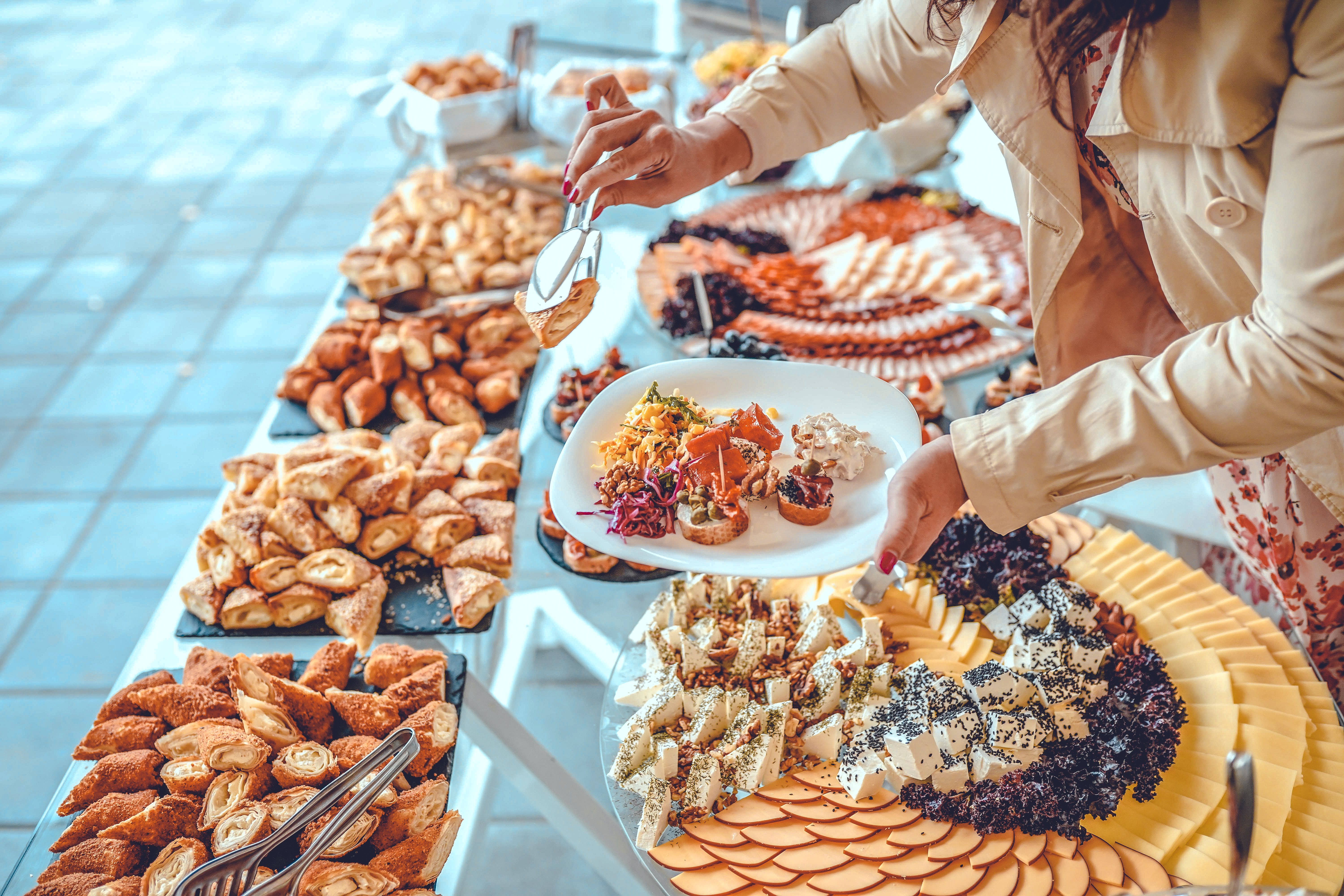 Woman holding plate and taking food from buffet table during breakfast in hotel Woman holding plate and taking food from buffet table during breakfast in hotel