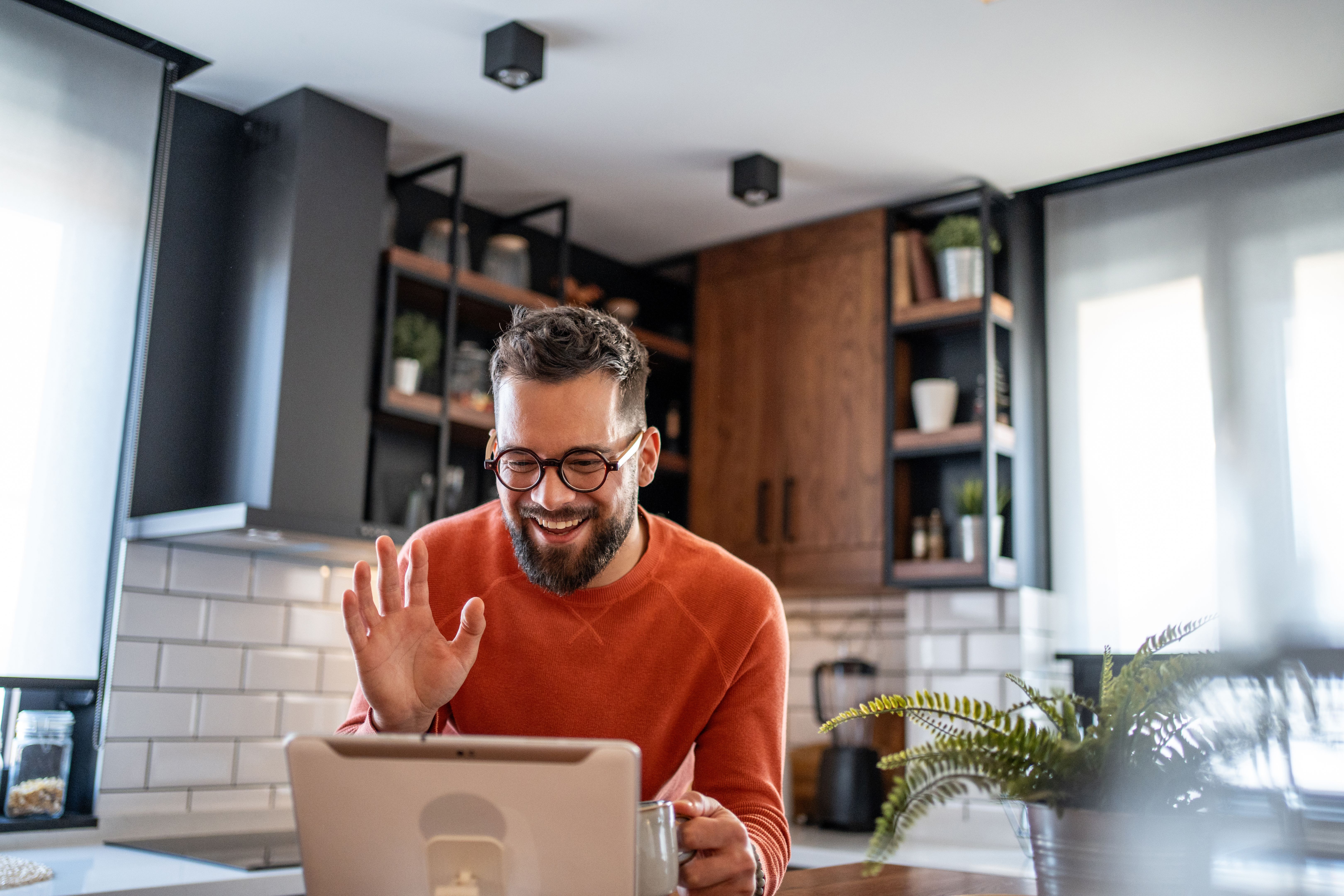 Young man in a Sage Collective meeting on his laptop in kitchen