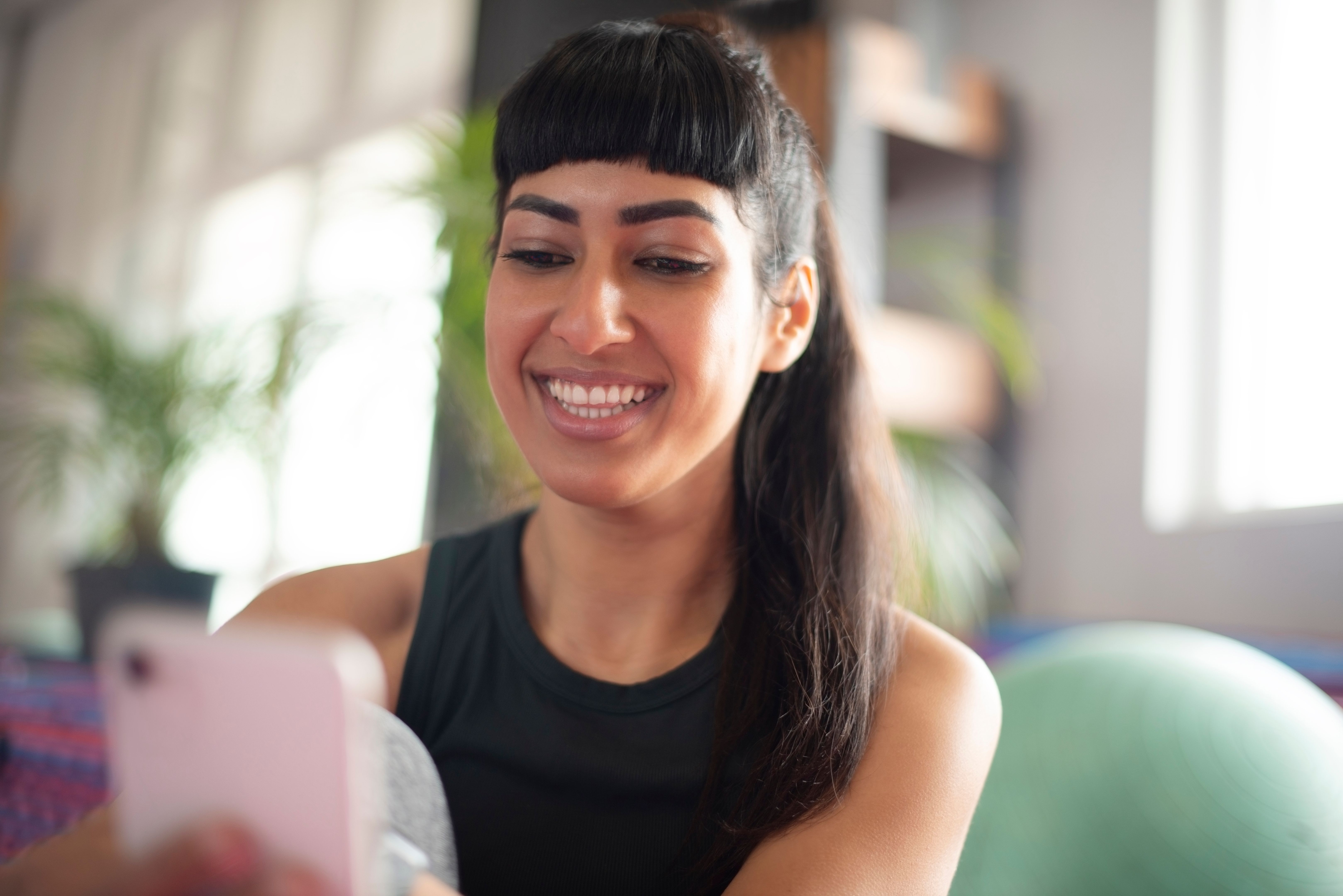 Téléphone, heureux et femme à la maison avec entraînement de fitness en ligne avec tutoriel sur l’application mobile. Sports, santé et femme personne avec téléphone portable pour lire l’exercice blog pour des conseils dans le salon de l’appart