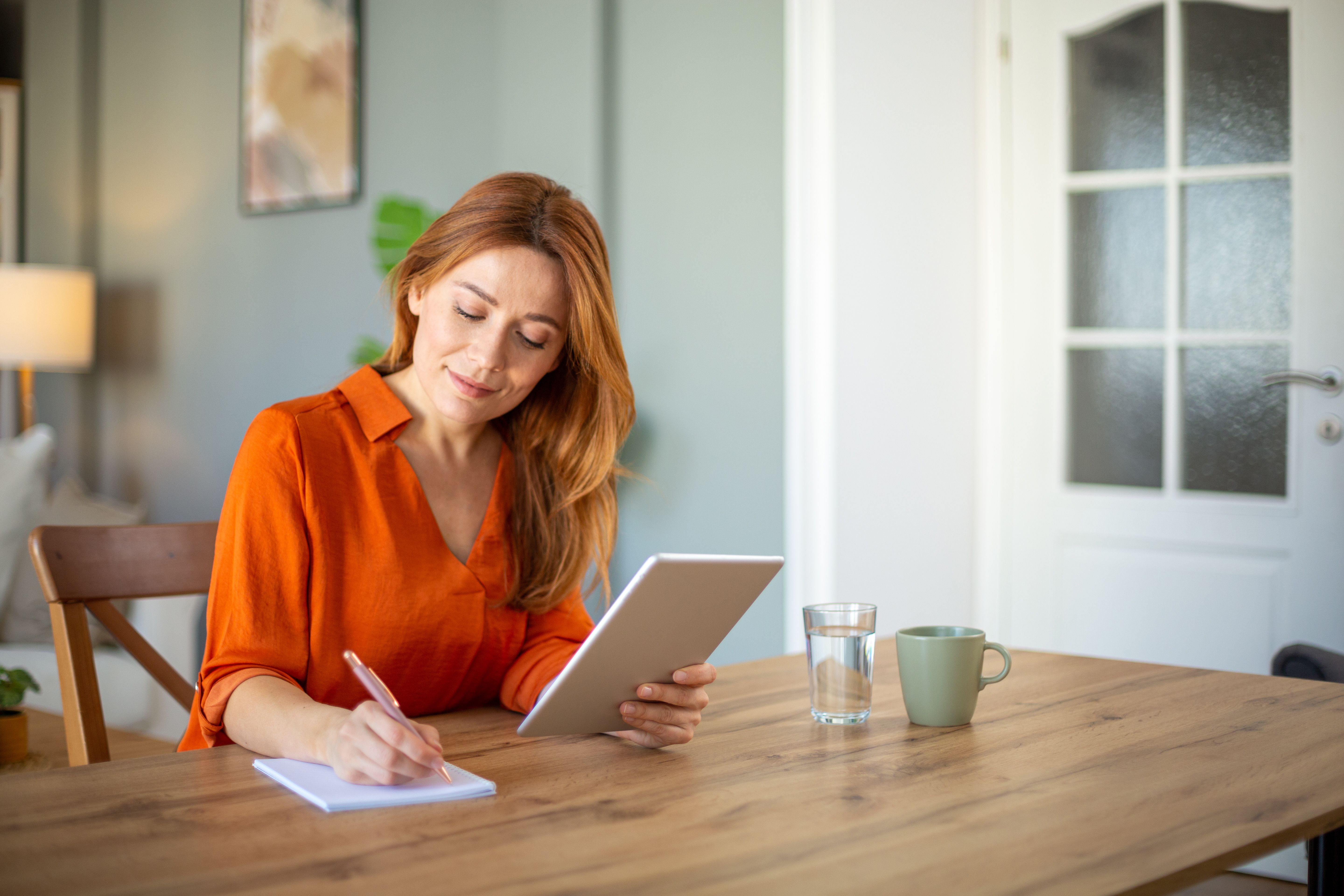 Smiling woman with digital tablet taking notes