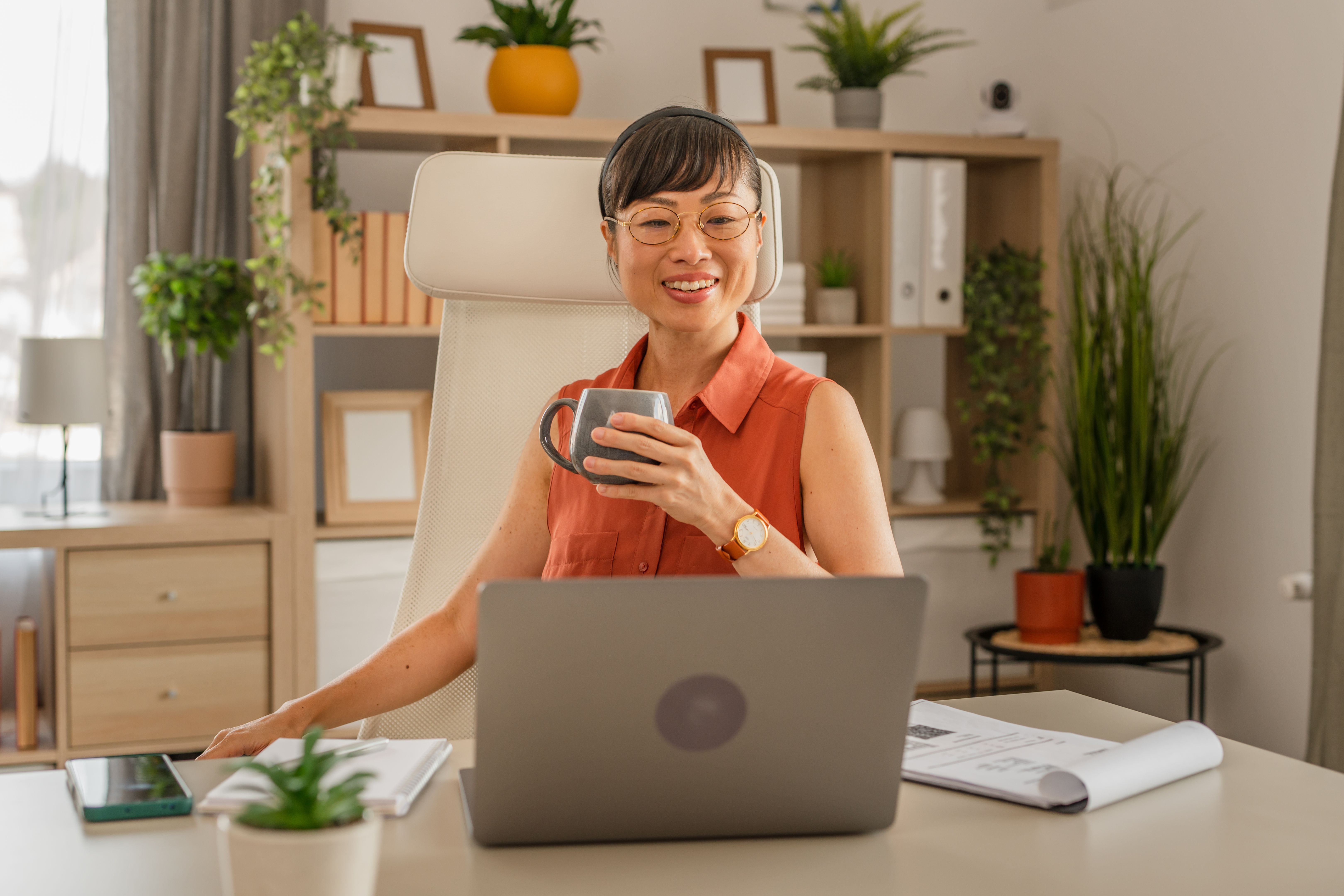 One Japanese woman working on laptop in the office and drinking coffee One Japanese woman working on laptop in the office and drinking coffee